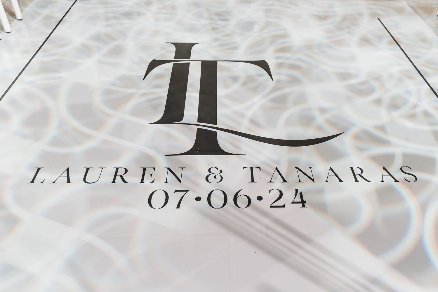 Custom monogram floor design reading 'Lauren & Tanaras 07-06-24' in elegant typography.