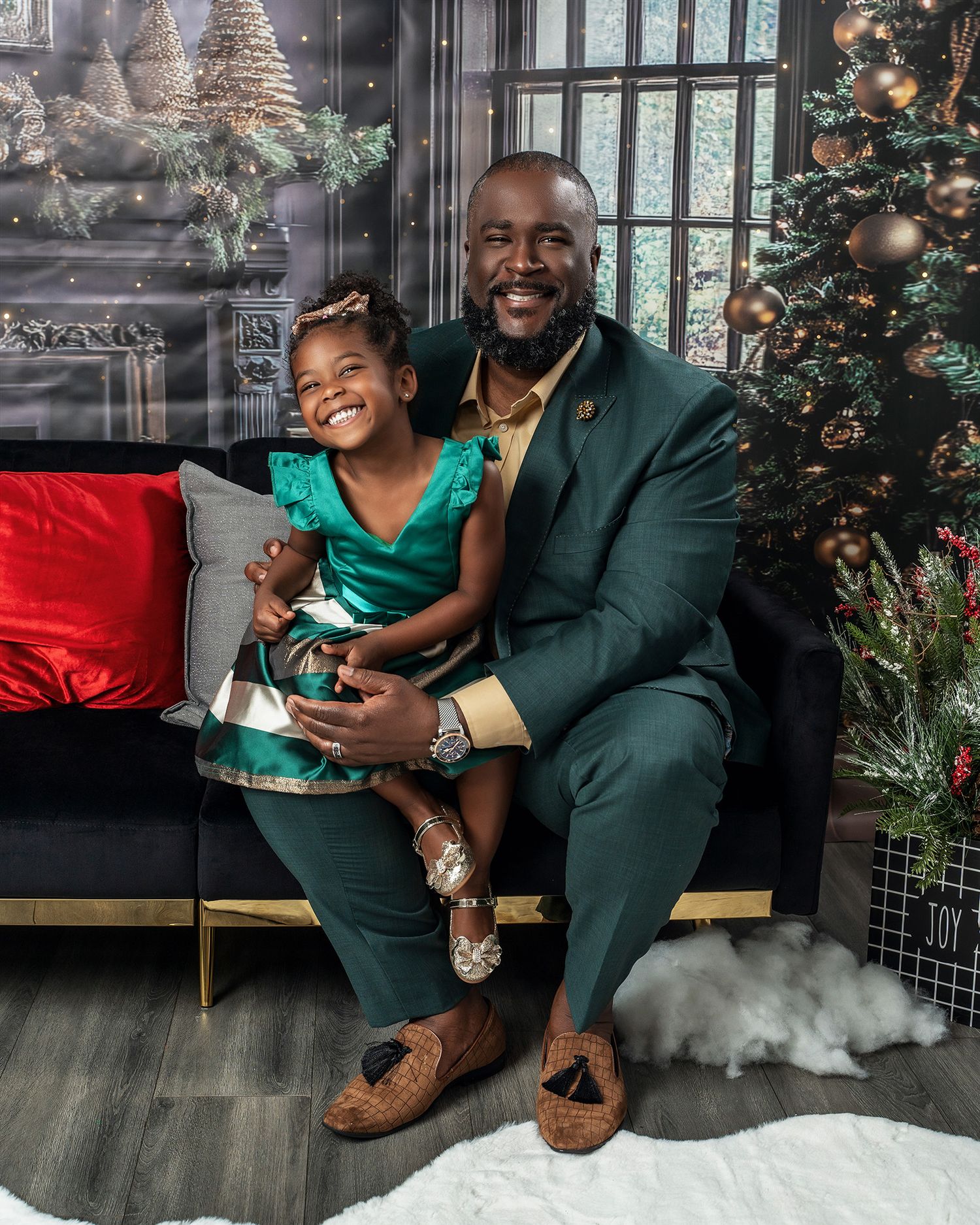 A cheerful holiday photo featuring green and dark formal attire against a decorated Christmas backdrop.
