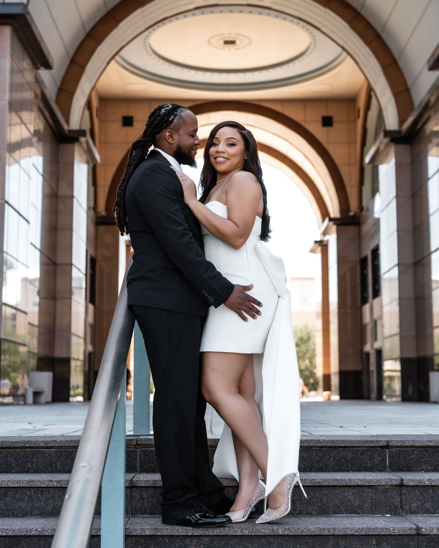 A romantic wedding photoshoot featuring elegant poses under ornate stone archways at a classical venue.