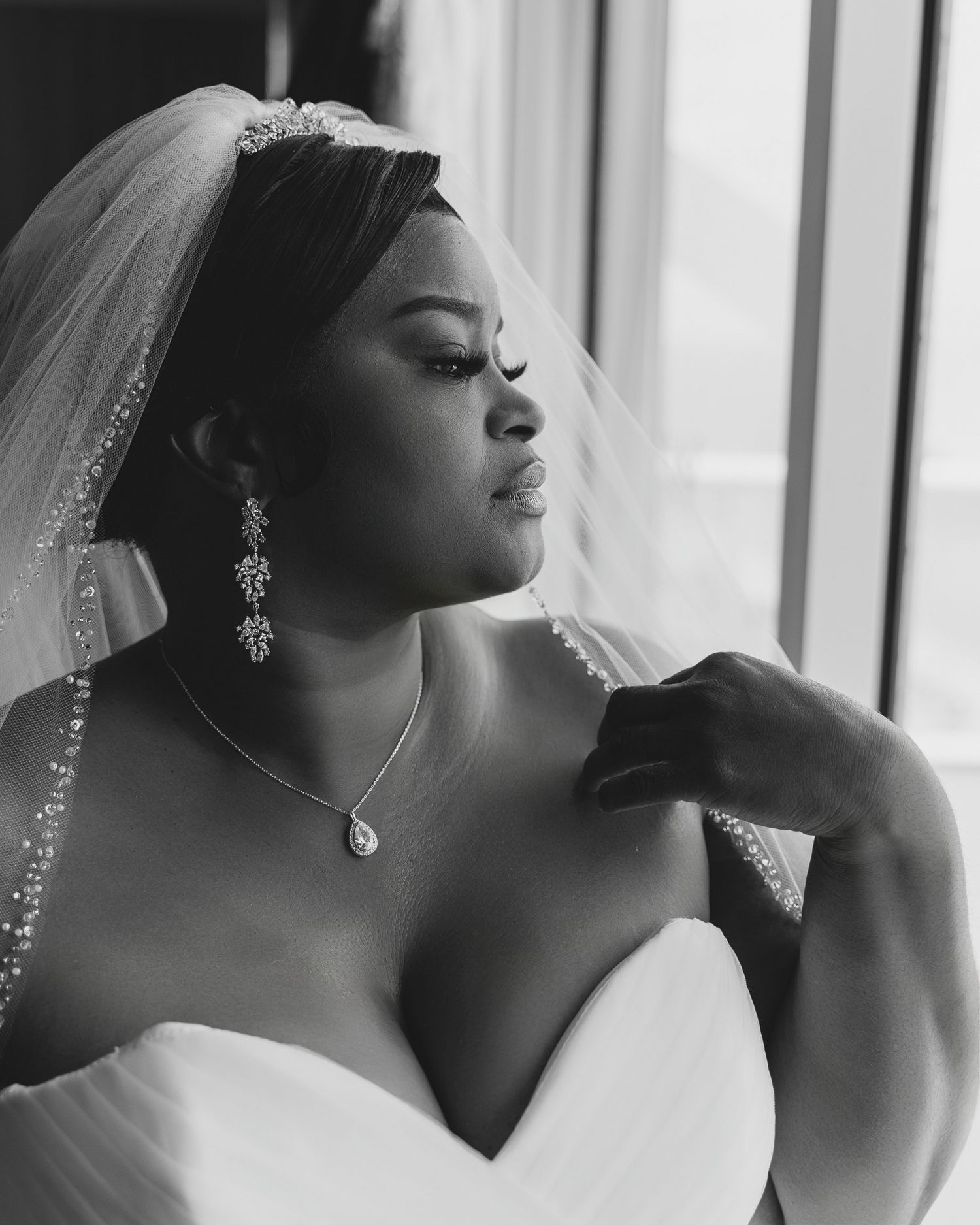 Elegant black and white bridal portrait showing jewelry and veil details.