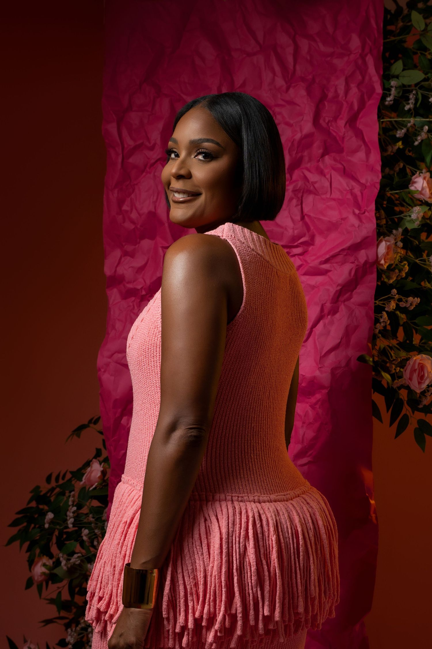 Portrait series against pink backdrop shows woman in pink fringed top posing in elegant profile positions.
