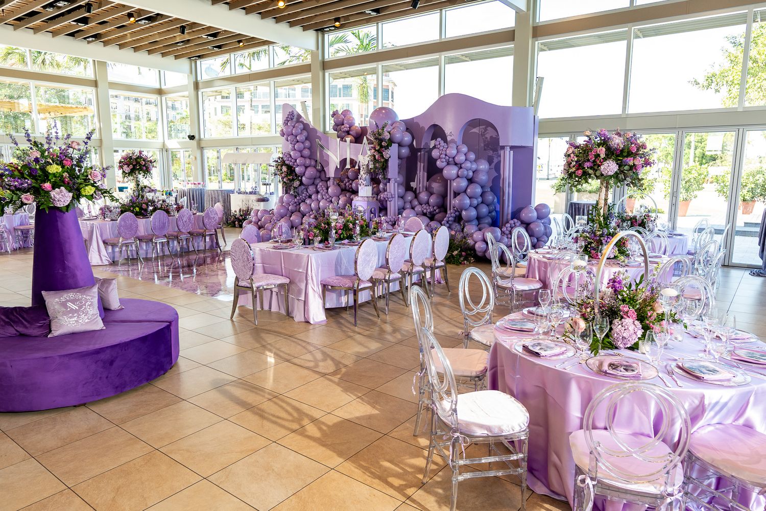 Elegant wedding reception venue decorated in shades of purple with floral centerpieces and luxurious table settings.