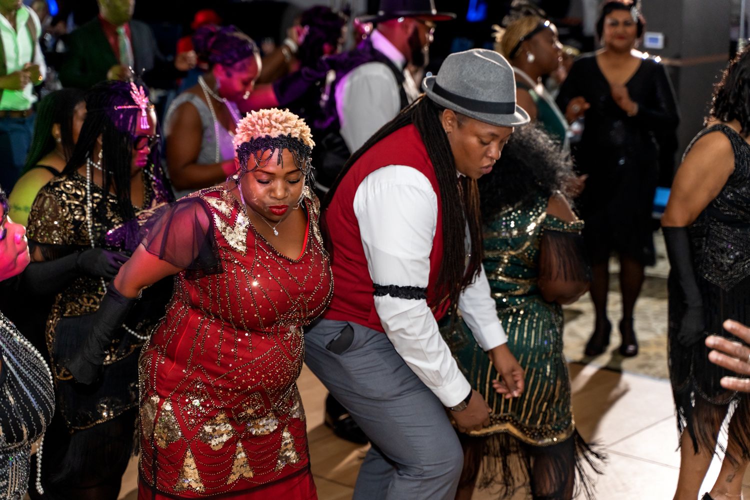Dancers in vintage-inspired outfits perform energetic moves at a themed party.