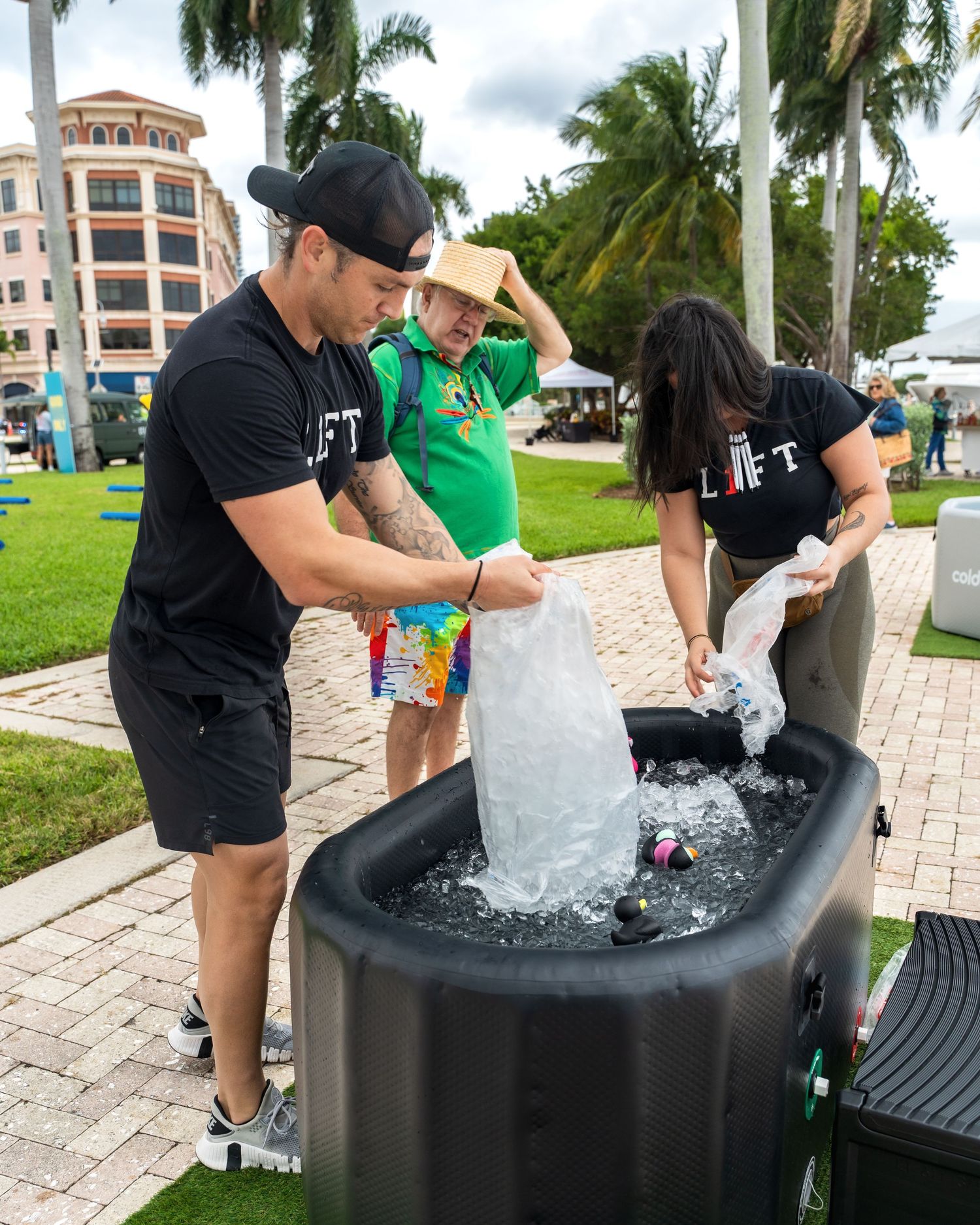 People getting refreshments from ice-filled cooler at outdoor event.