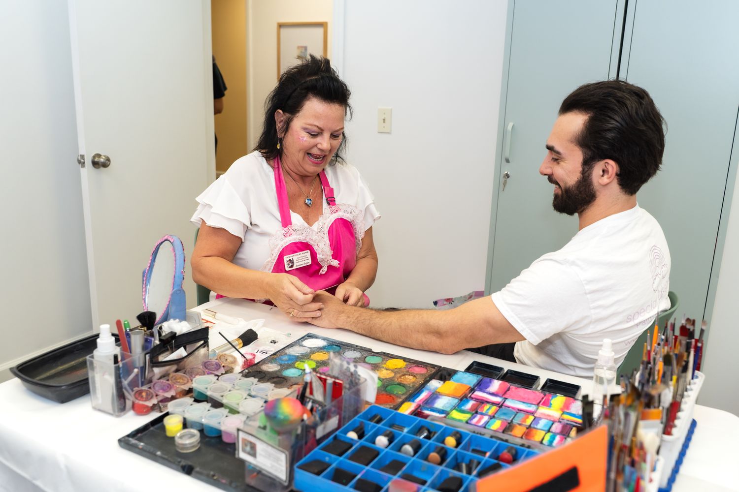 Woman giving manicure service to client at nail salon desk with organized polish and tools.