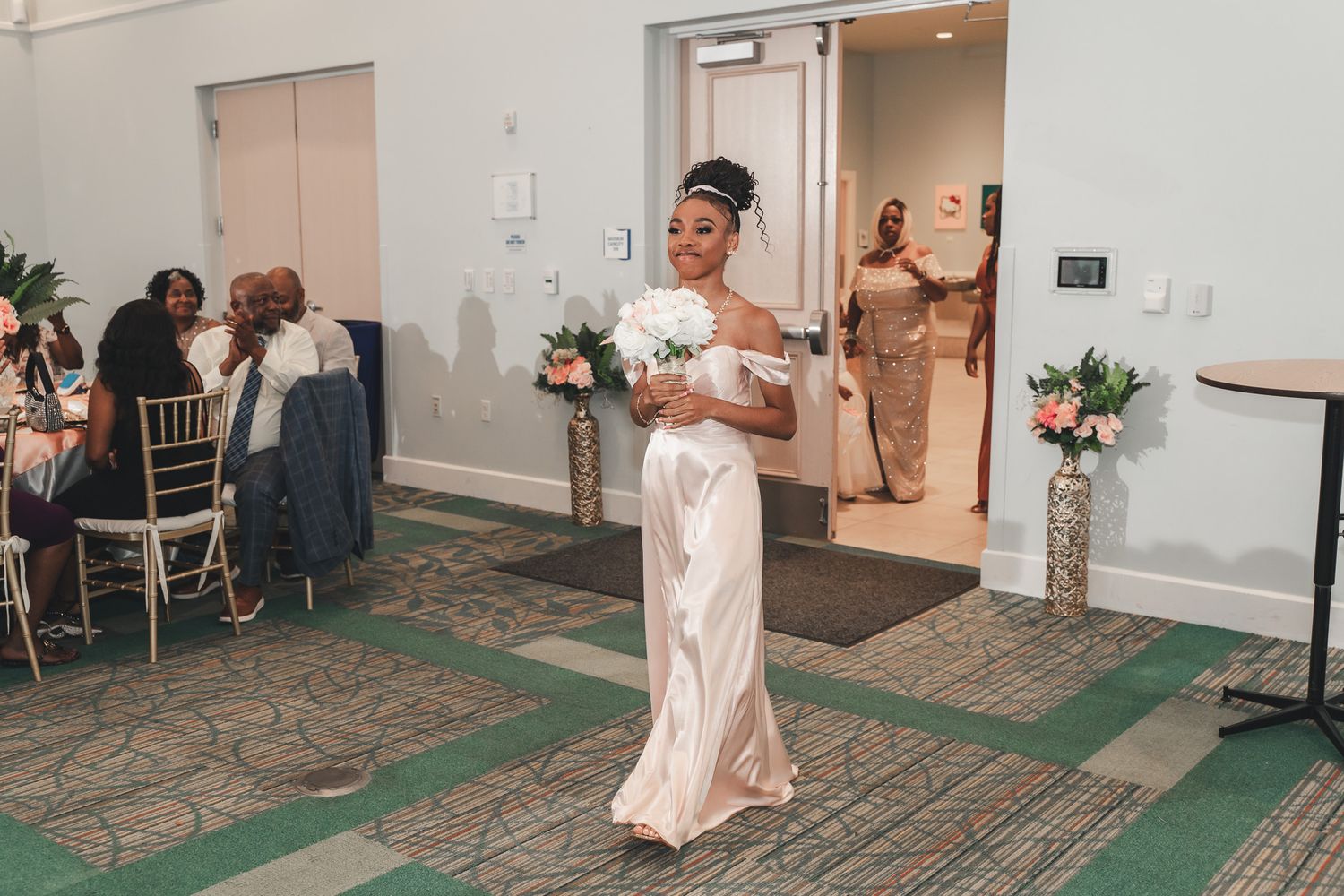 A bride in a white gown holds a bouquet while walking down the aisle.