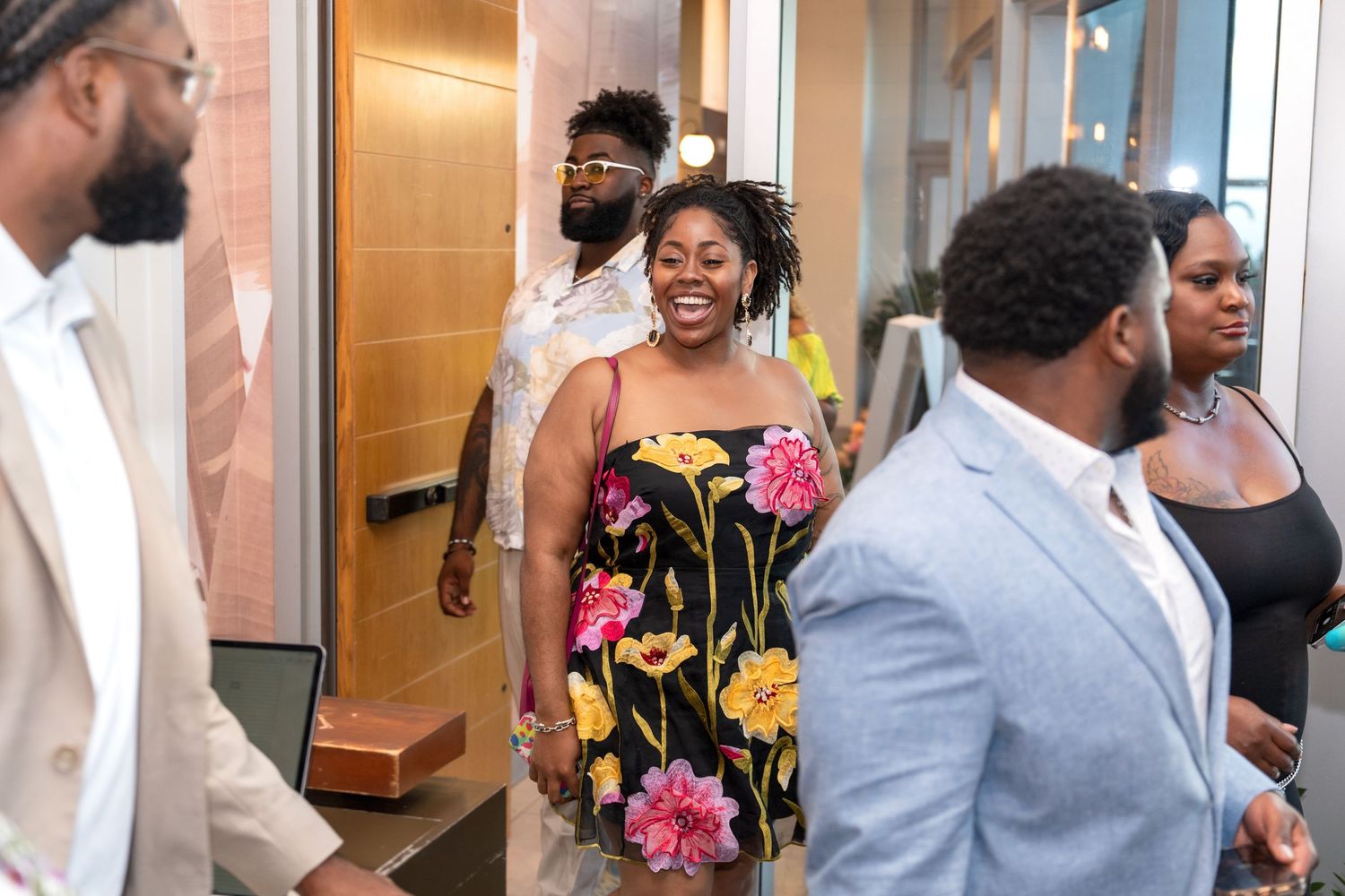 People walking and smiling in an office hallway with wooden doors.