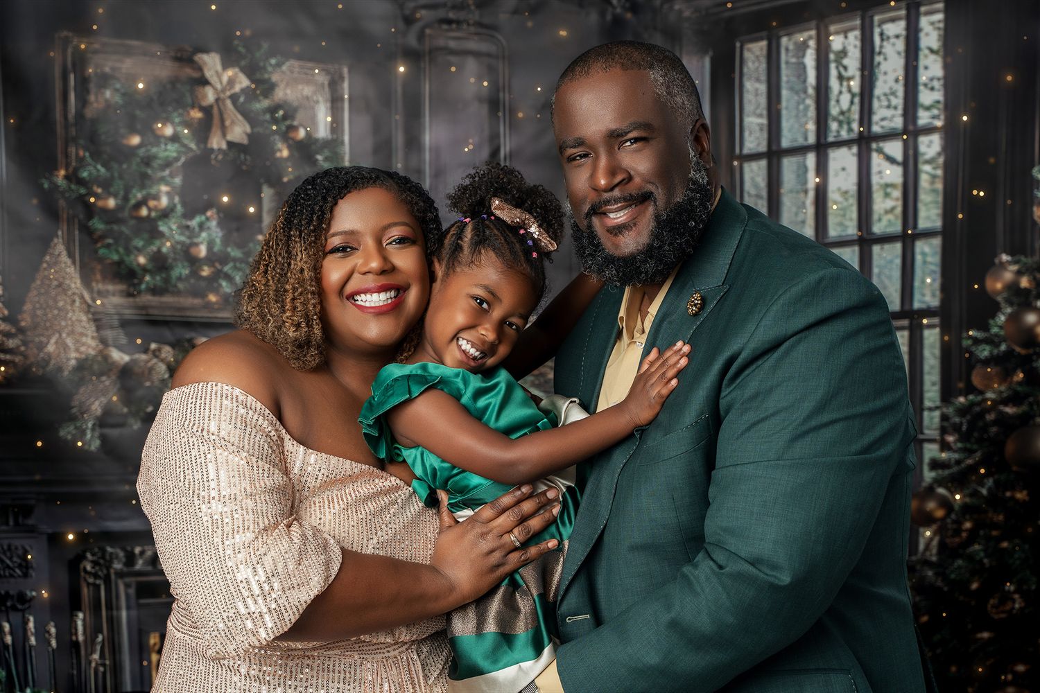 A family poses together in coordinated formal wear with Christmas trees in the background.