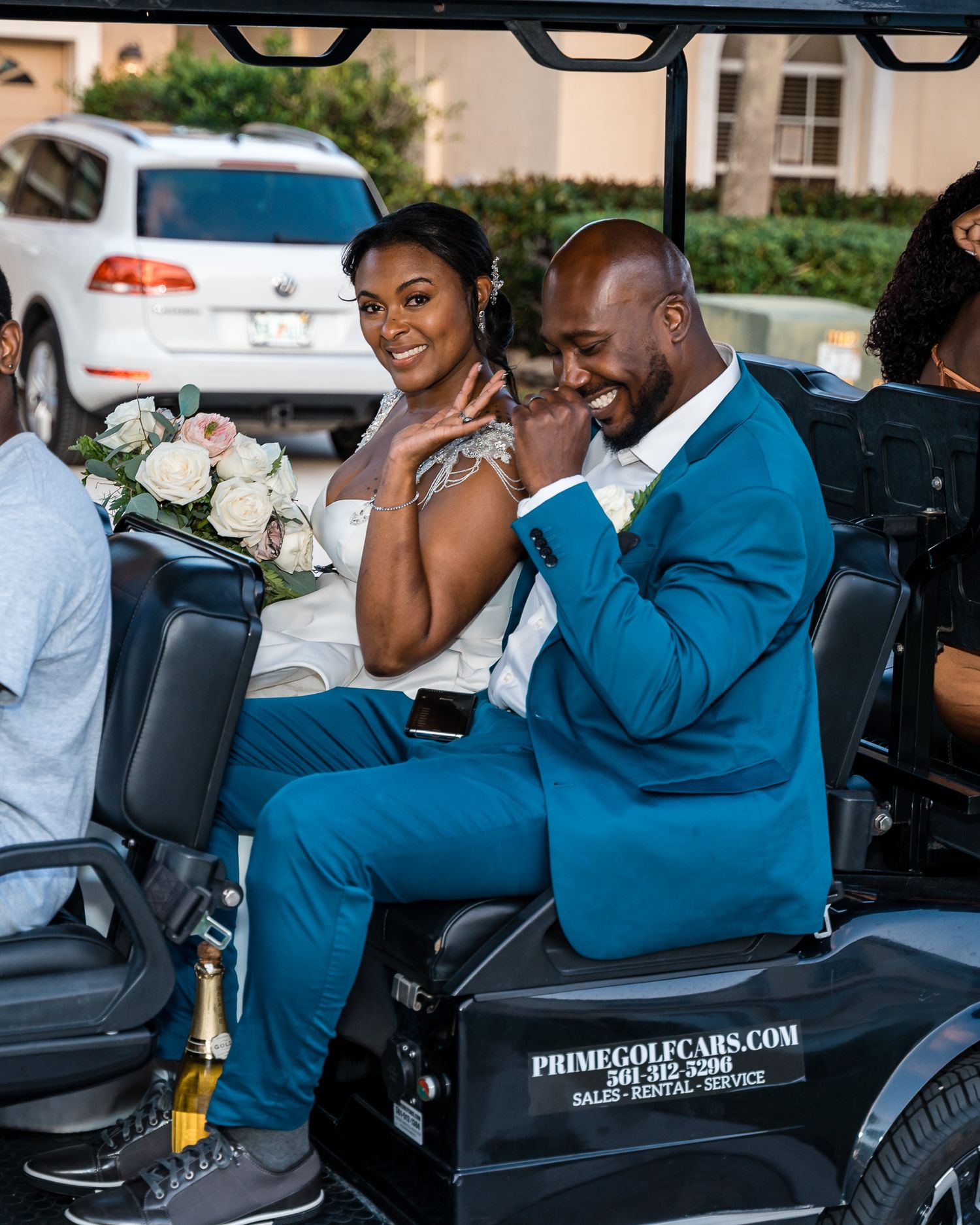Wedding couple riding in a decorated golf cart wearing formal attire.