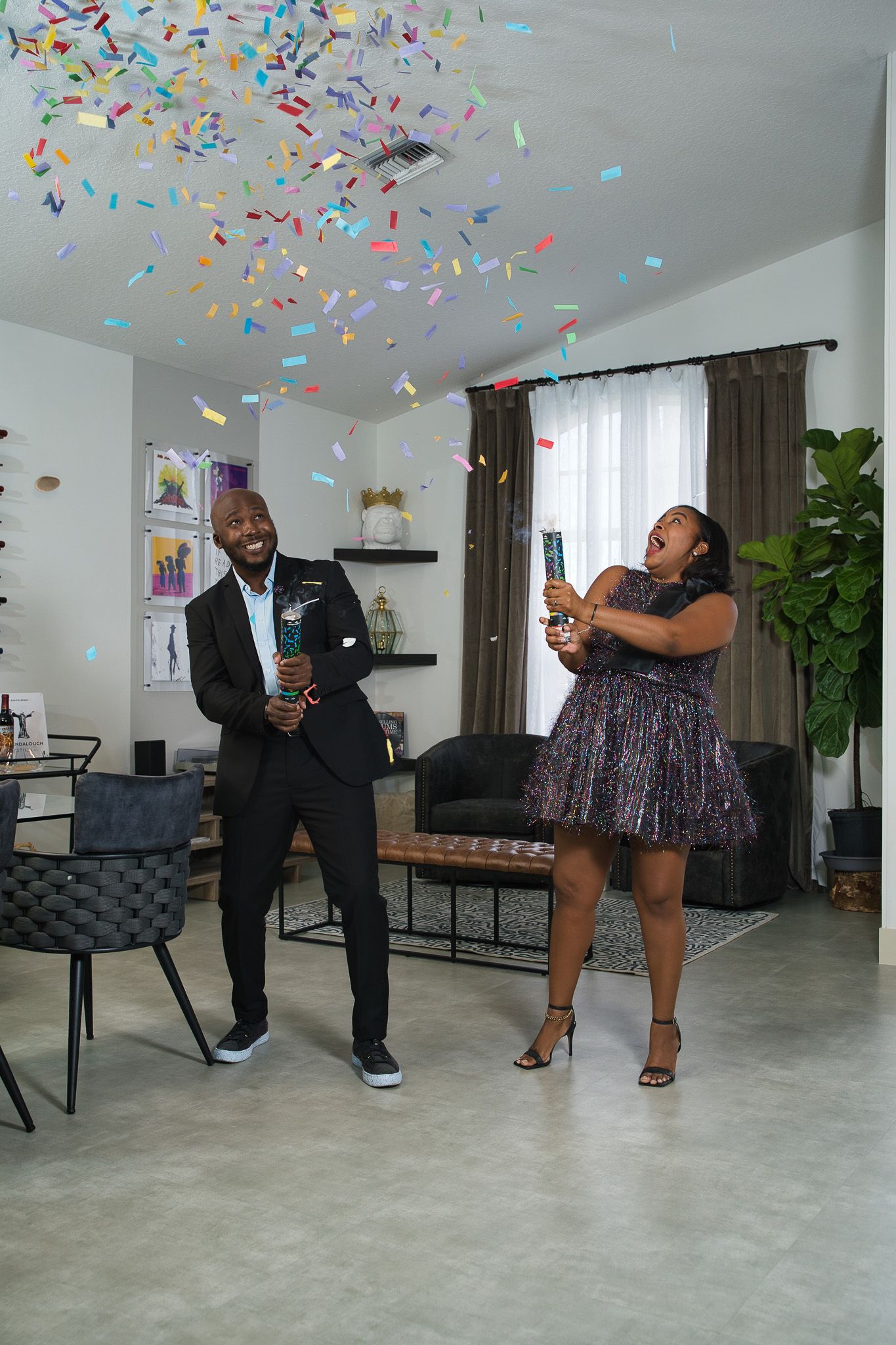 Couple celebrating with confetti in modern living room with geometric decor.