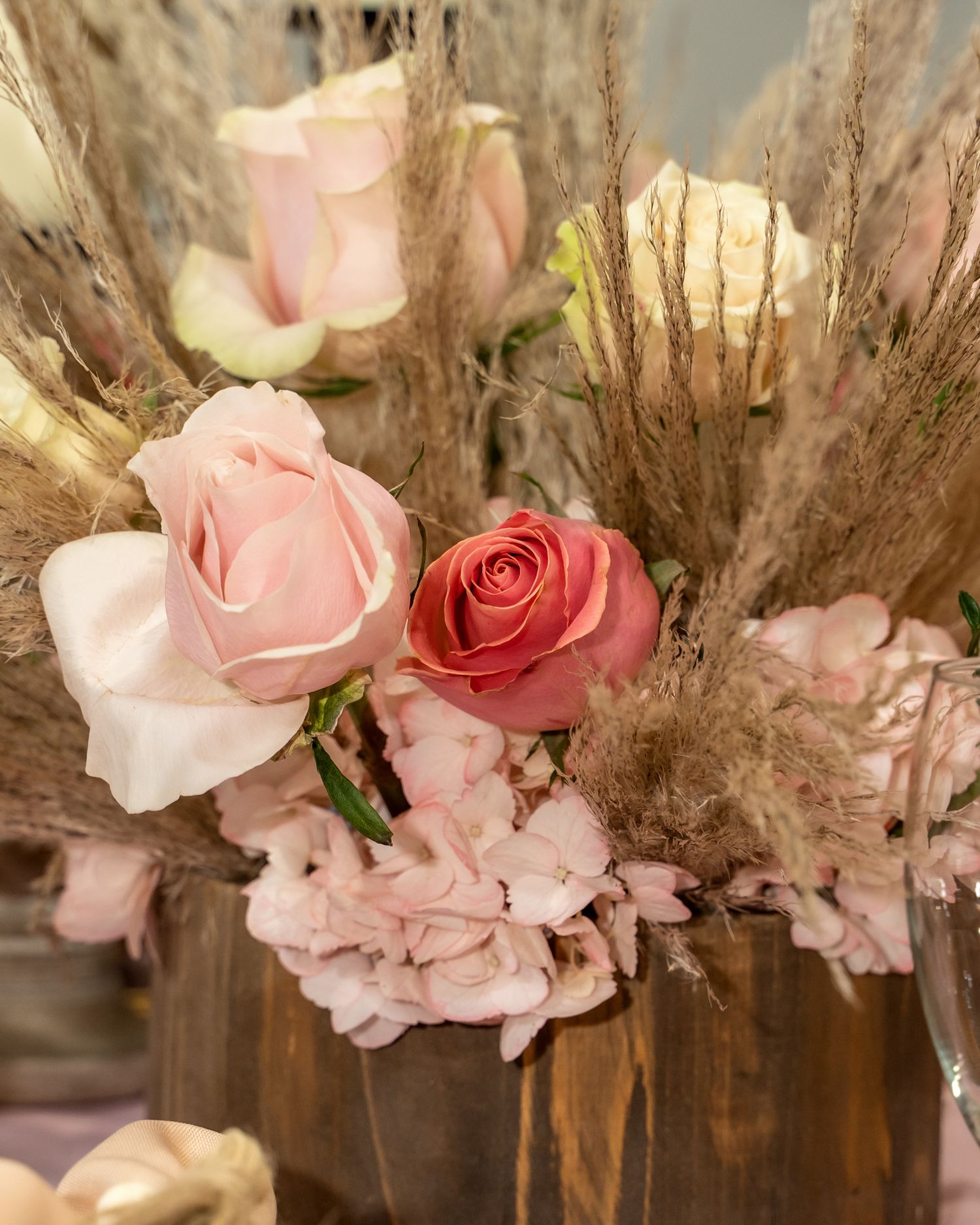 Delicate pink roses and dried pampas grass floral arrangement in neutral tones.