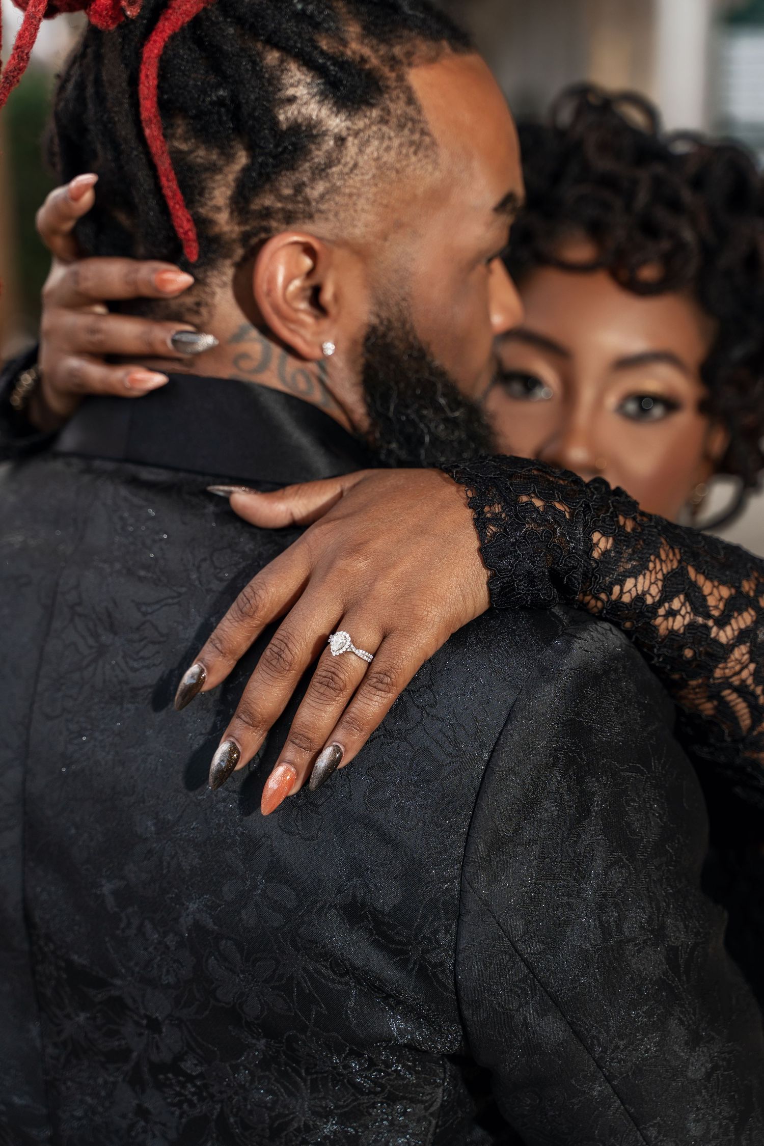 Close-up sequence showing a tender embrace with hands displaying an engagement ring against black lace clothing.