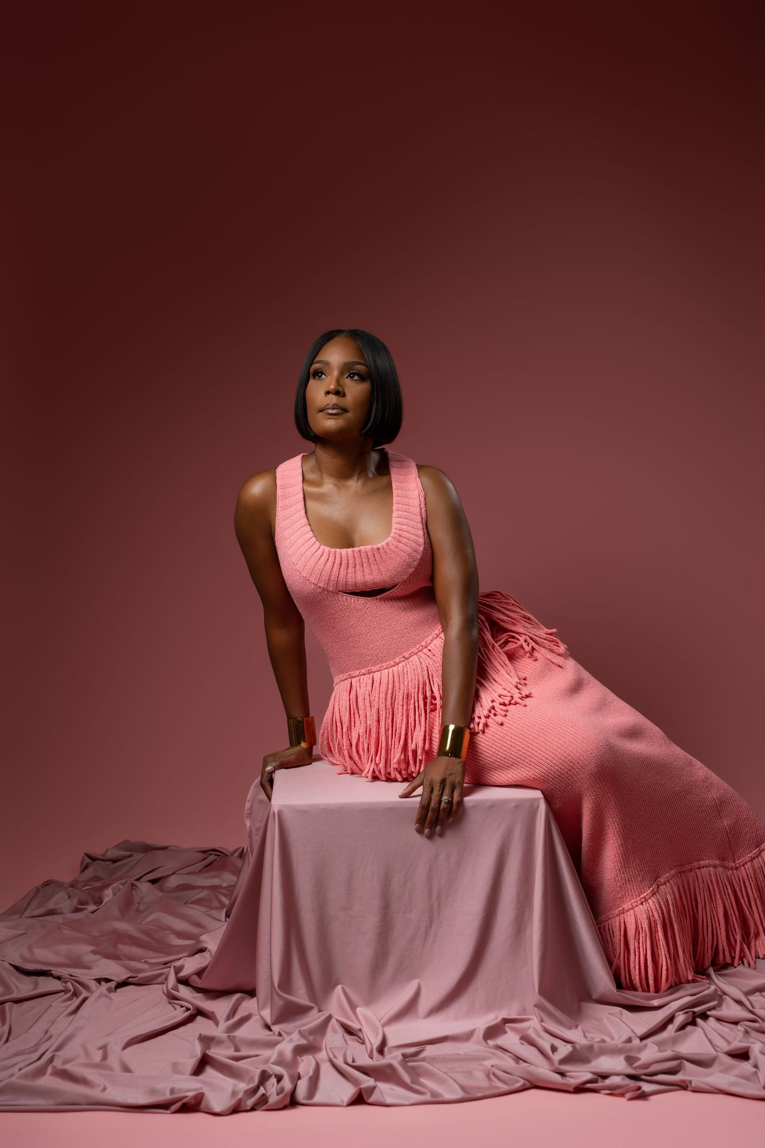 A person in a pink tank top reclines gracefully on flowing pink fabric in an artistic fashion portrait series.
