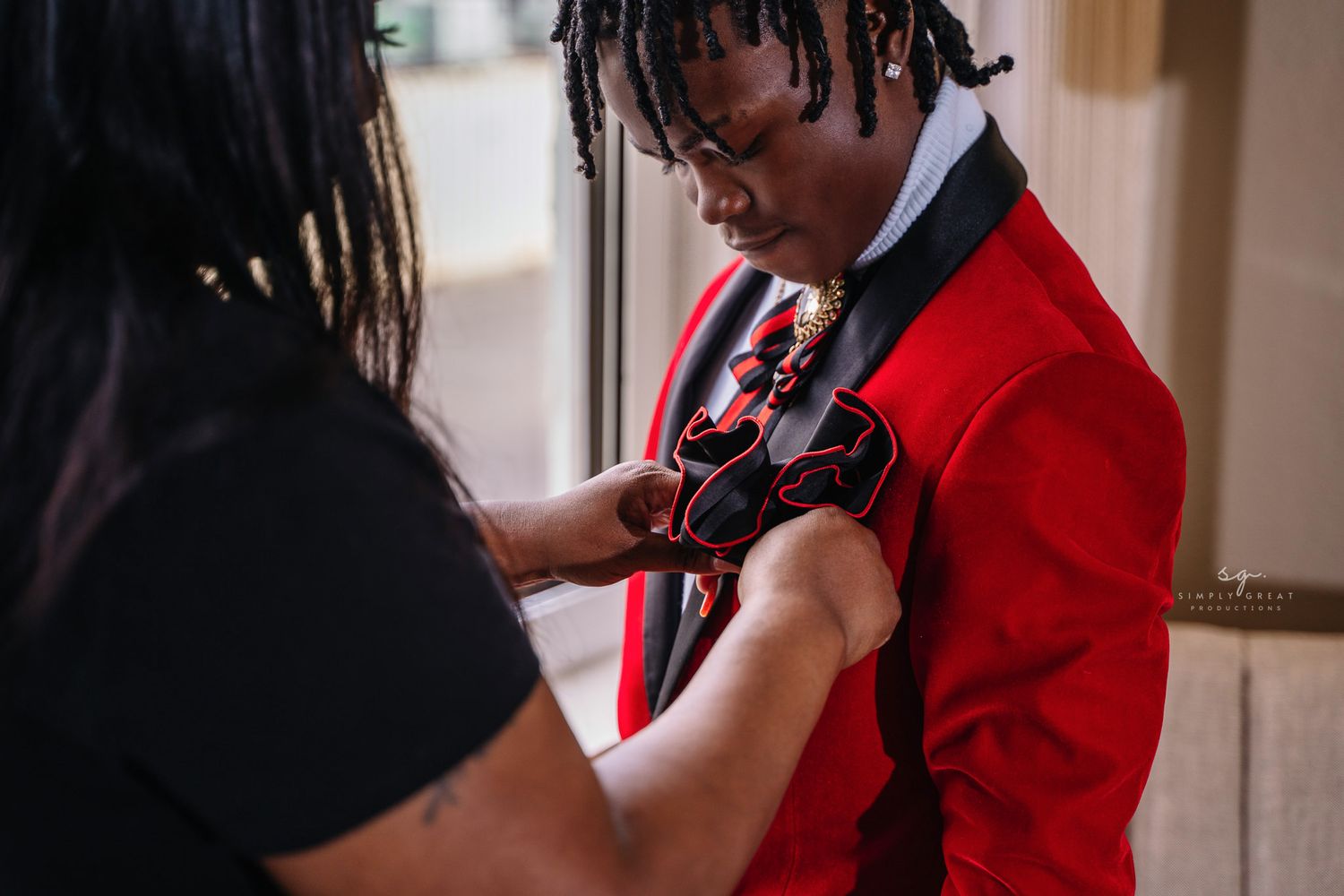 Final adjustments being made to red formal suit jacket before event.