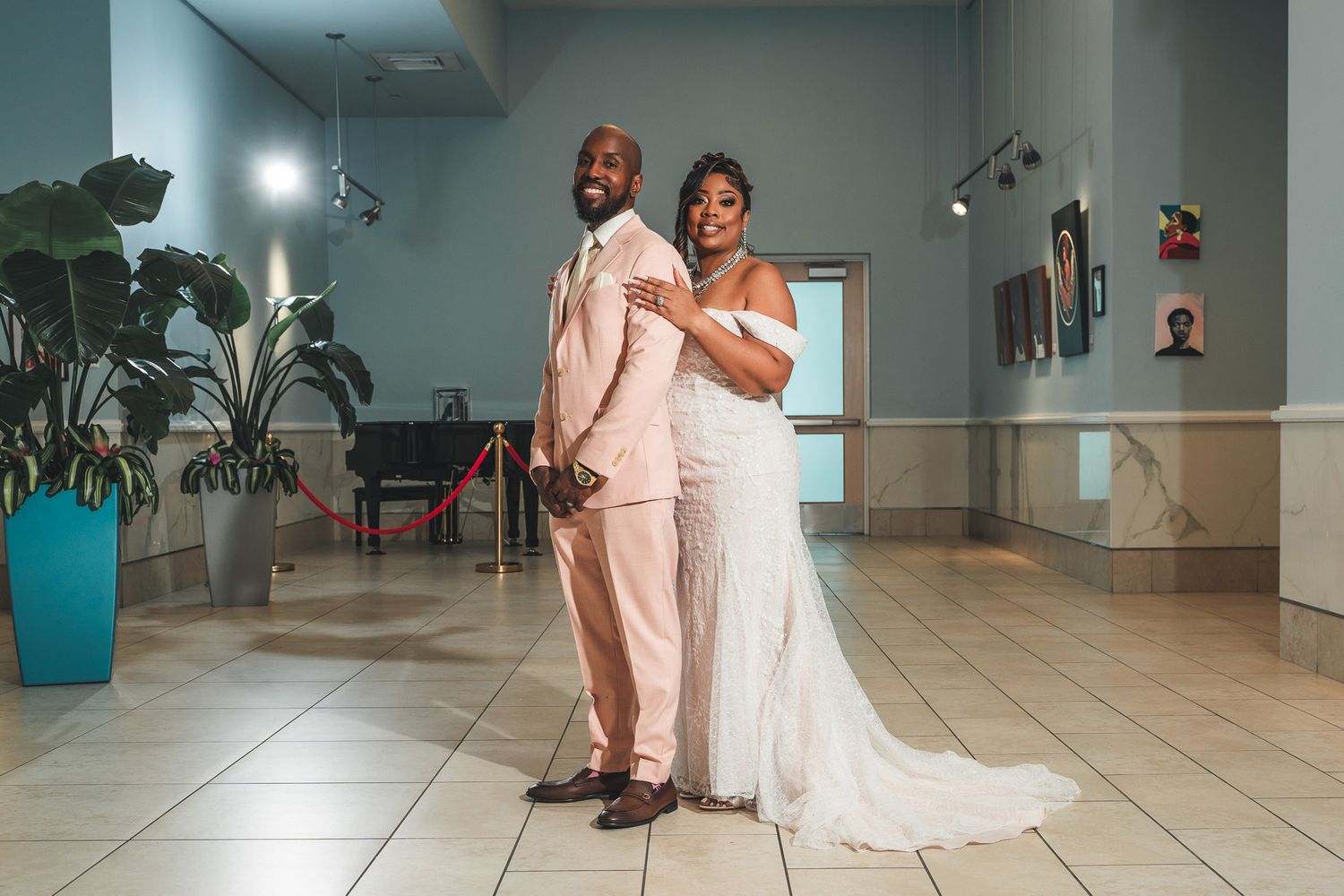 Newlyweds share a joyful moment on their wedding day in a tiled reception venue.