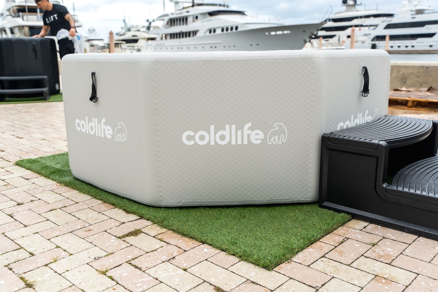 Gray Coldlife branded cooler placed on artificial turf near brick pavement.