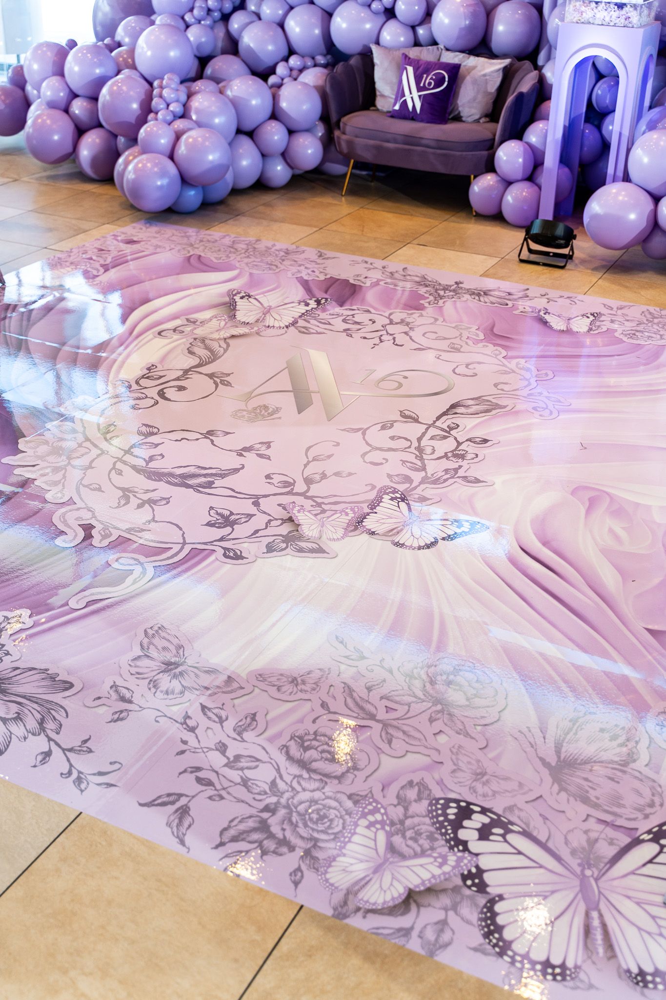 Custom floor decal with butterfly and floral design surrounded by purple balloon decorations.