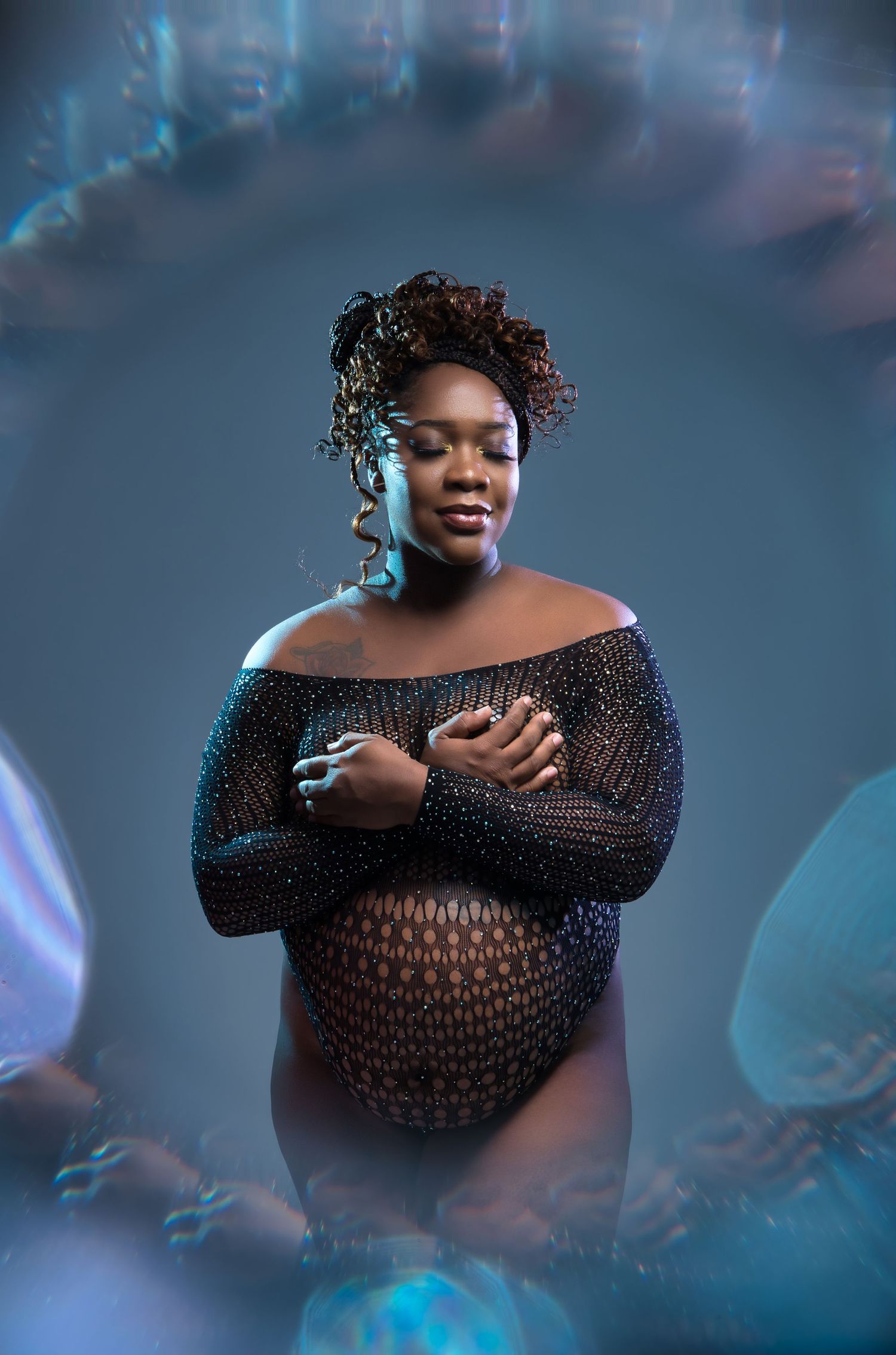 Ethereal maternity portrait with sparkling overlay effects and sheer black dress.