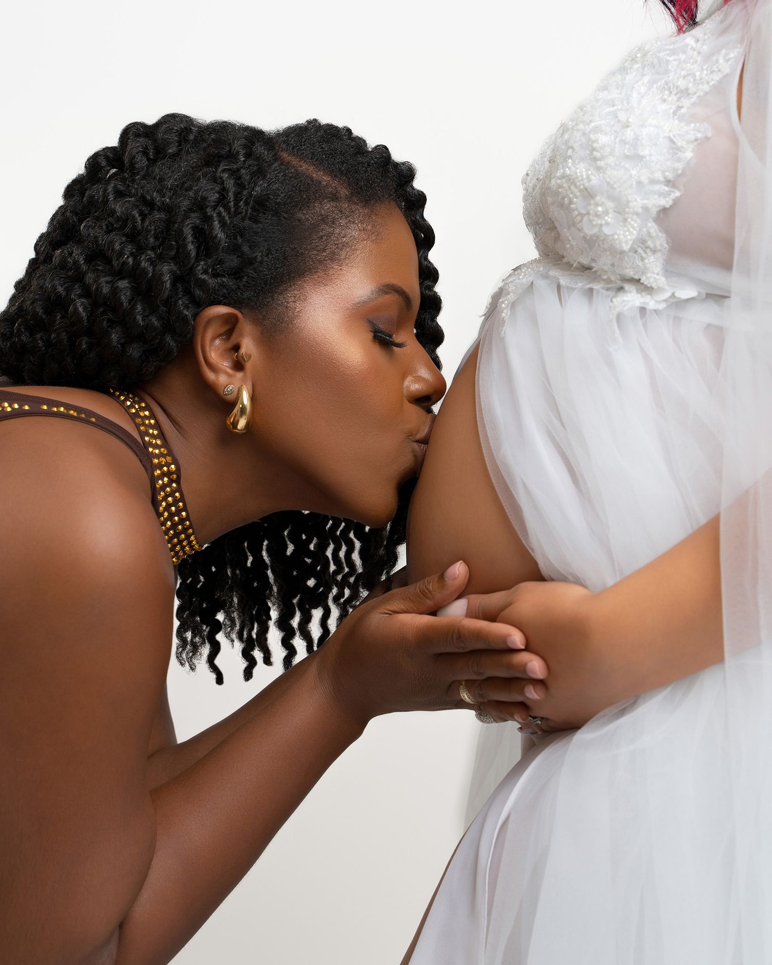 Intimate maternity moment captured in white lace dress.