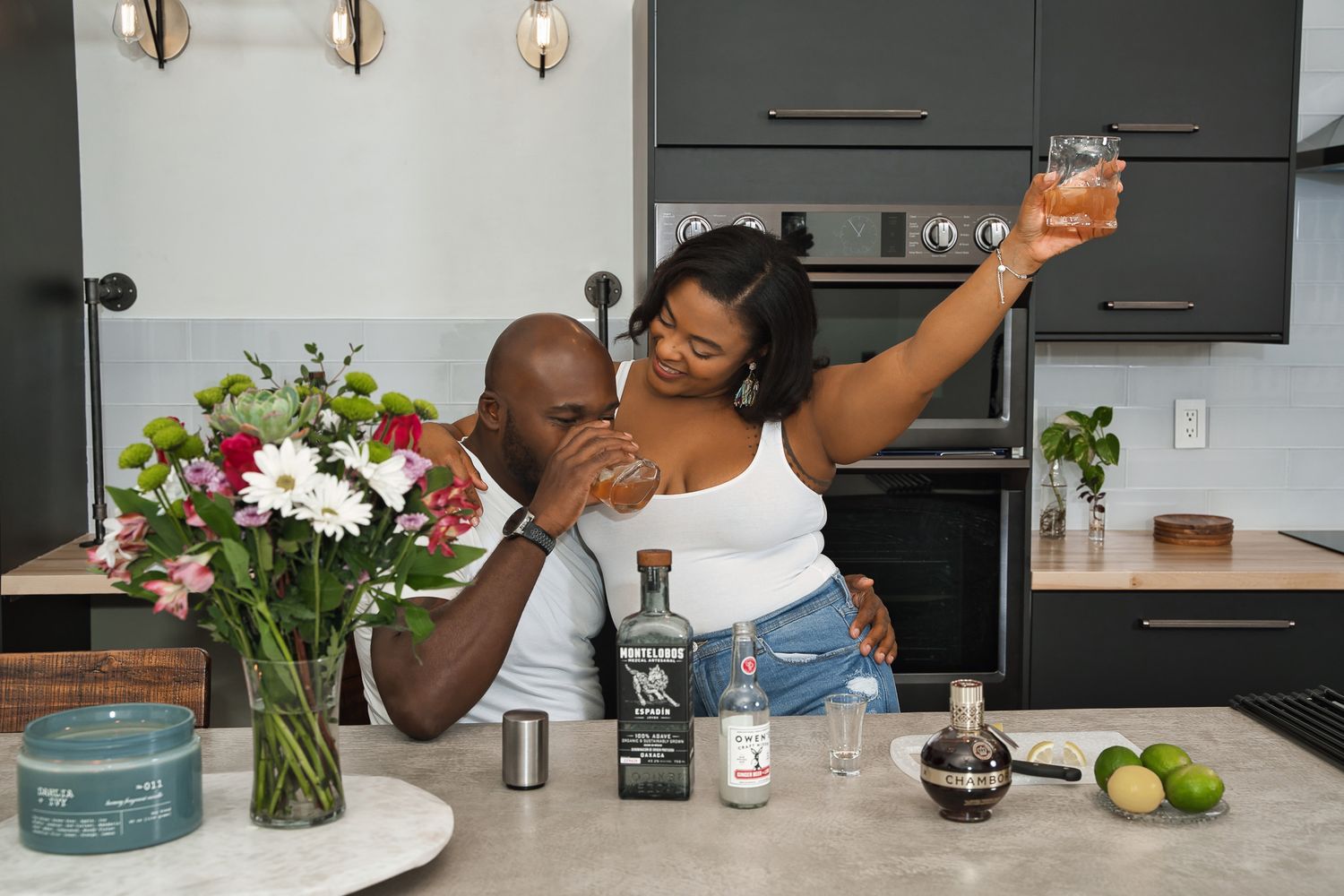 A playful moment shared between a couple while making drinks in their kitchen.