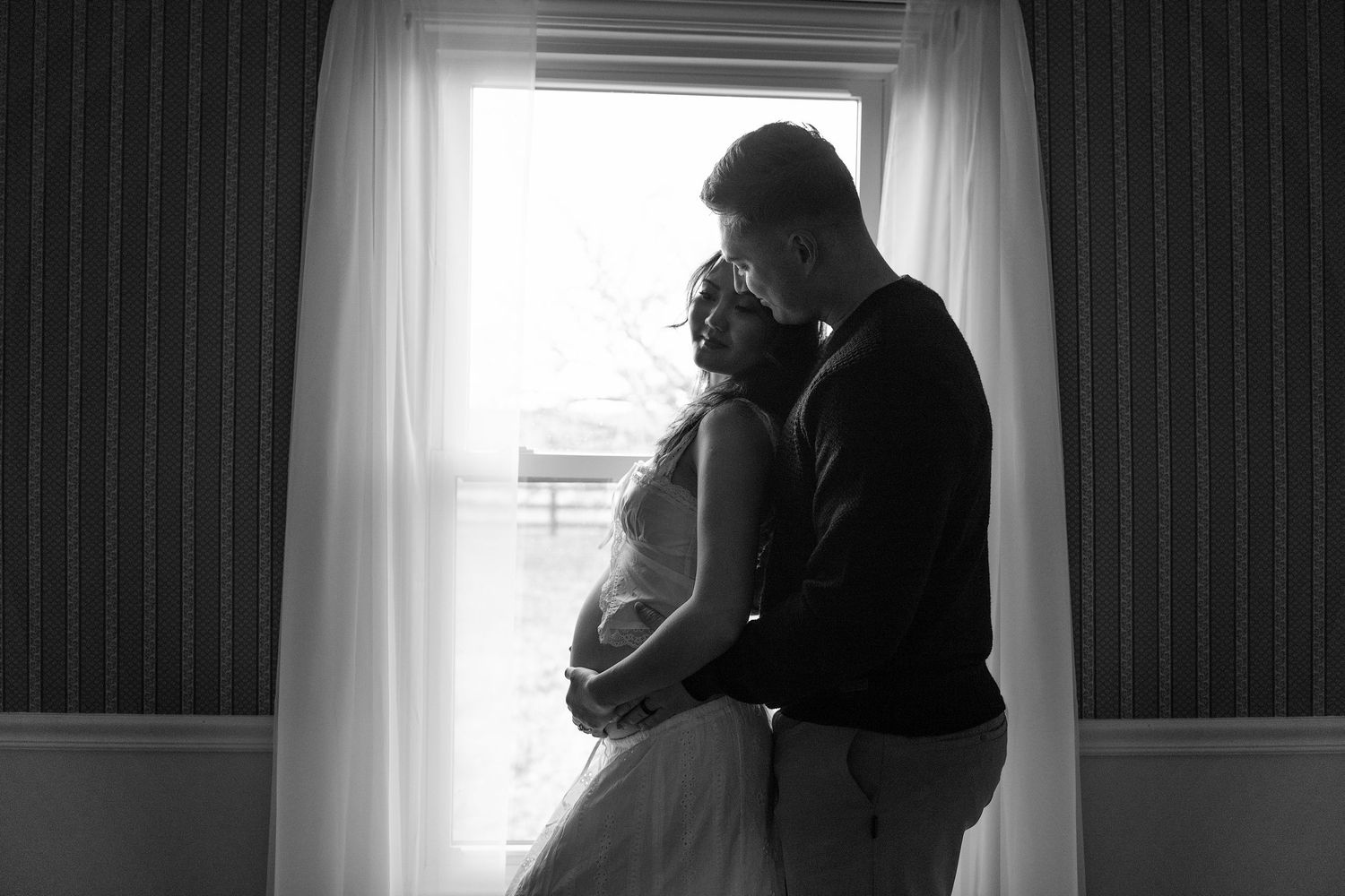 A series of black and white silhouettes show intimate moments between a couple by a window.