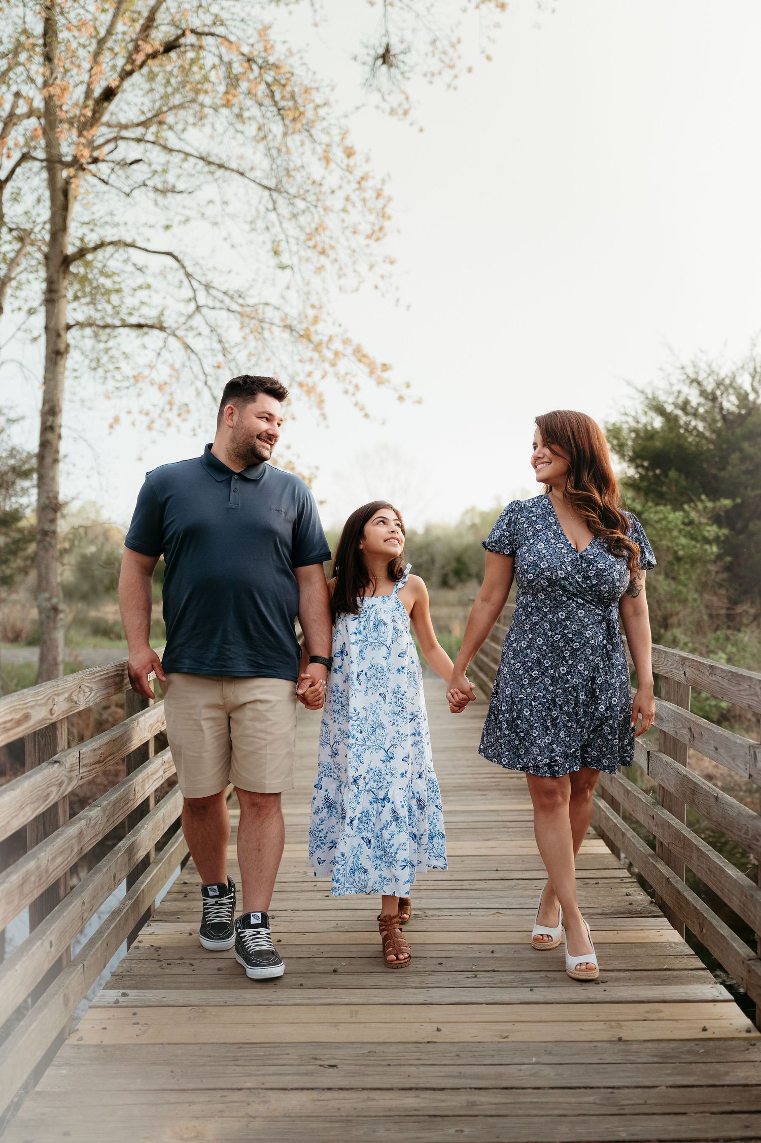 Family walking together on a wooden bridge pathway surrounded by autumn trees on a bright day in Haymarket Virginia.