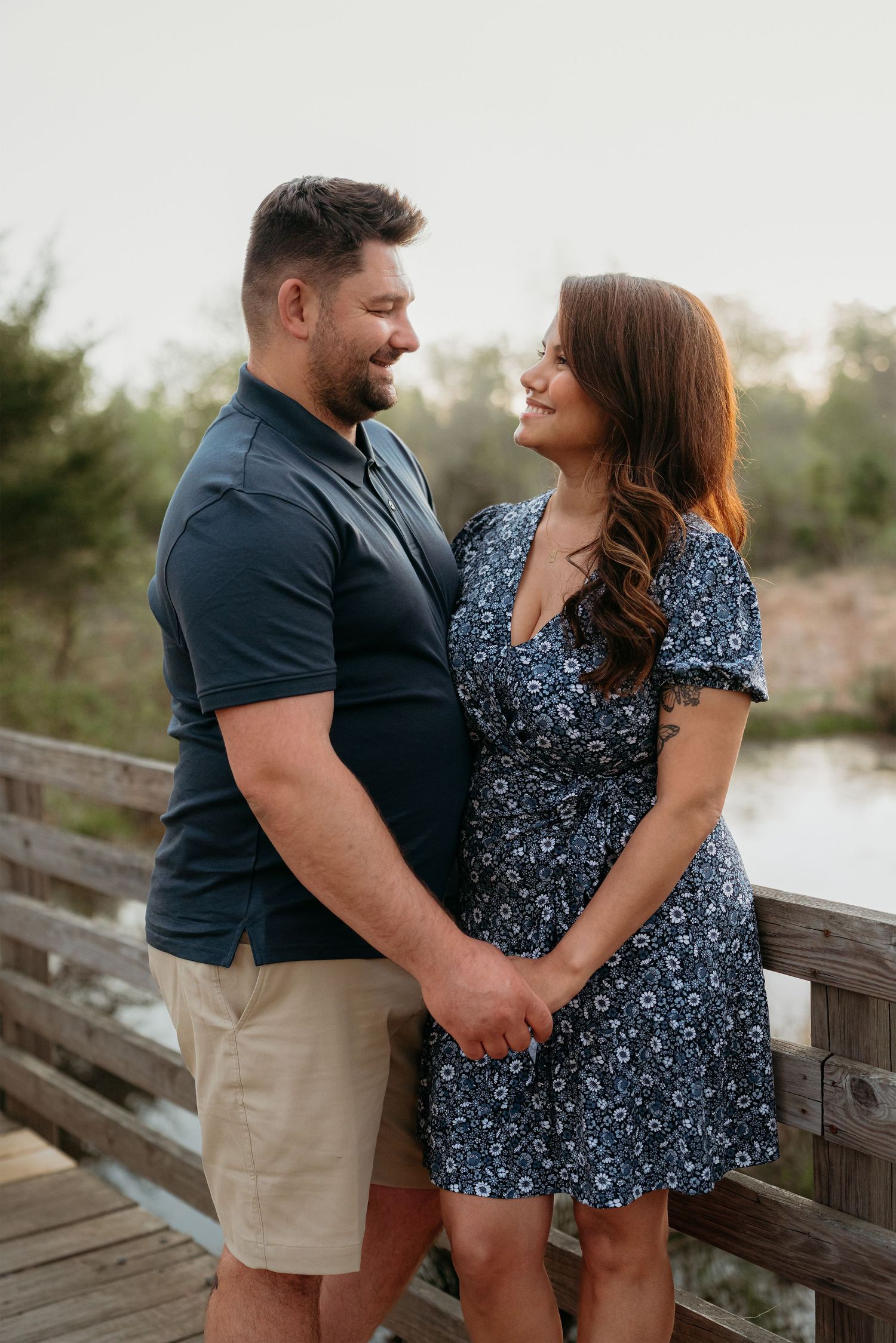 A couple shares romantic moments on a wooden boardwalk by a lake during sunset in Haymarket Virginia.