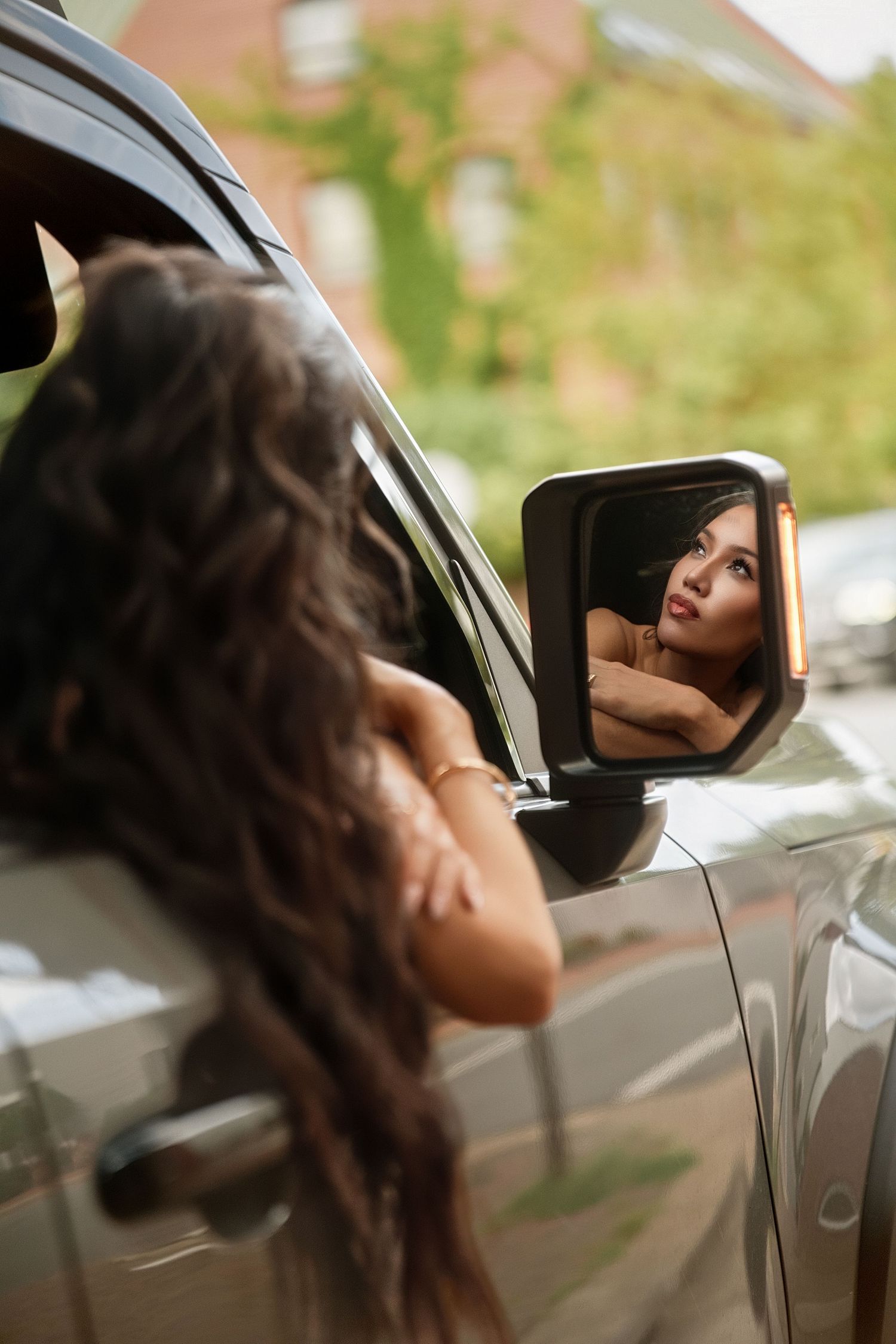 Artistic car photoshoot featuring long dark hair flowing in natural lighting.