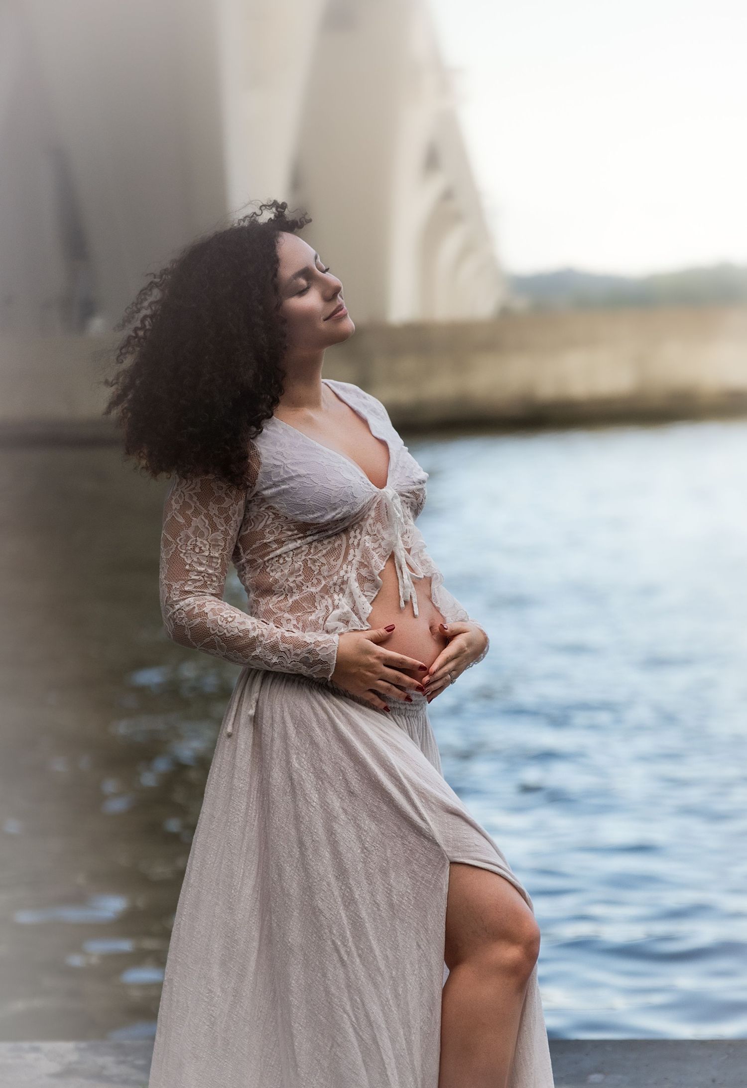 Waterfront maternity photos at dusk featuring lace and tulle gown.