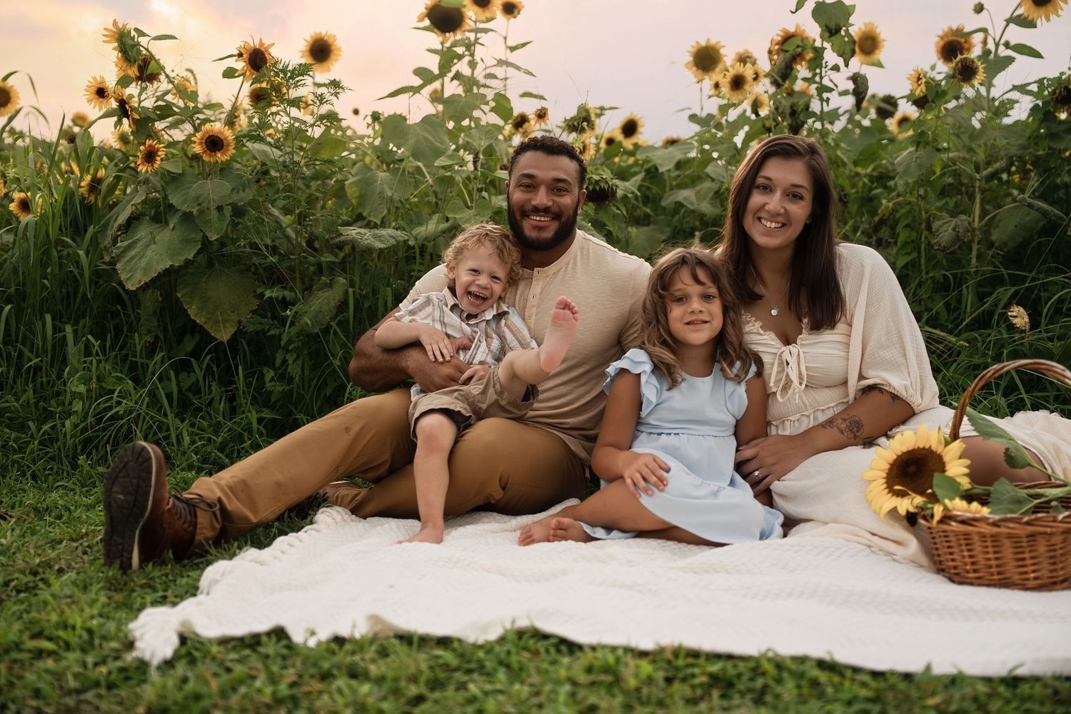 Couple having intimate picnic photoshoot in sunflower field during sunset.