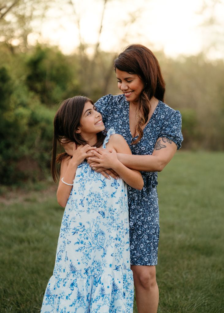Motherly connection with daughter, blue floral dresses share playful moments together in an outdoor setting at sunset in Haymarket, virginia