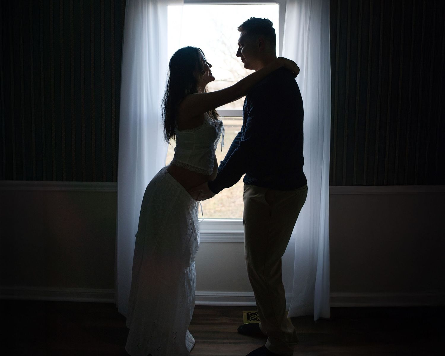 Silhouetted figures in dramatic lighting create a series of intimate dance-like poses against a bright window background.