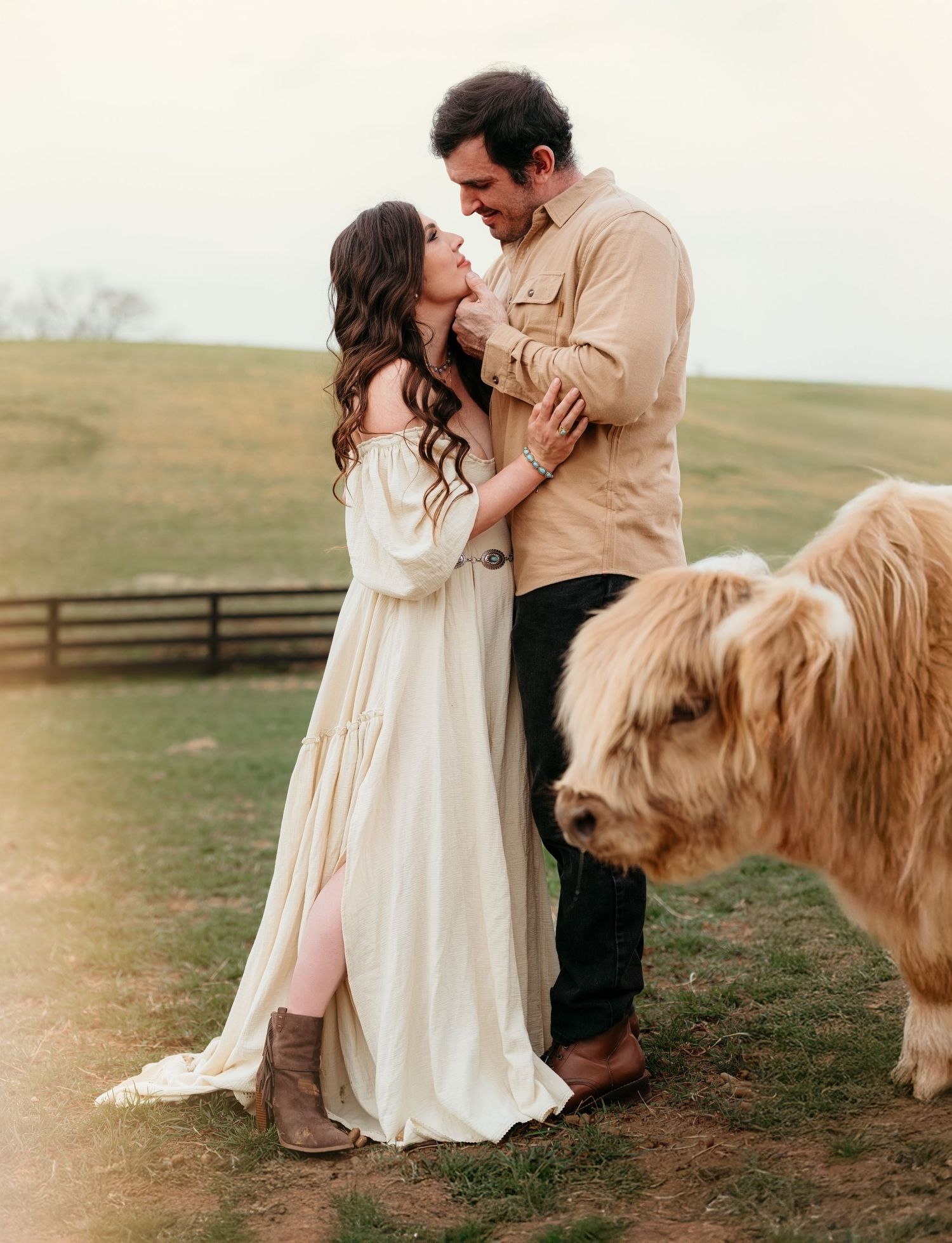 Couple in formal wear sharing tender moments with fluffy cream-colored pony in pastoral setting.