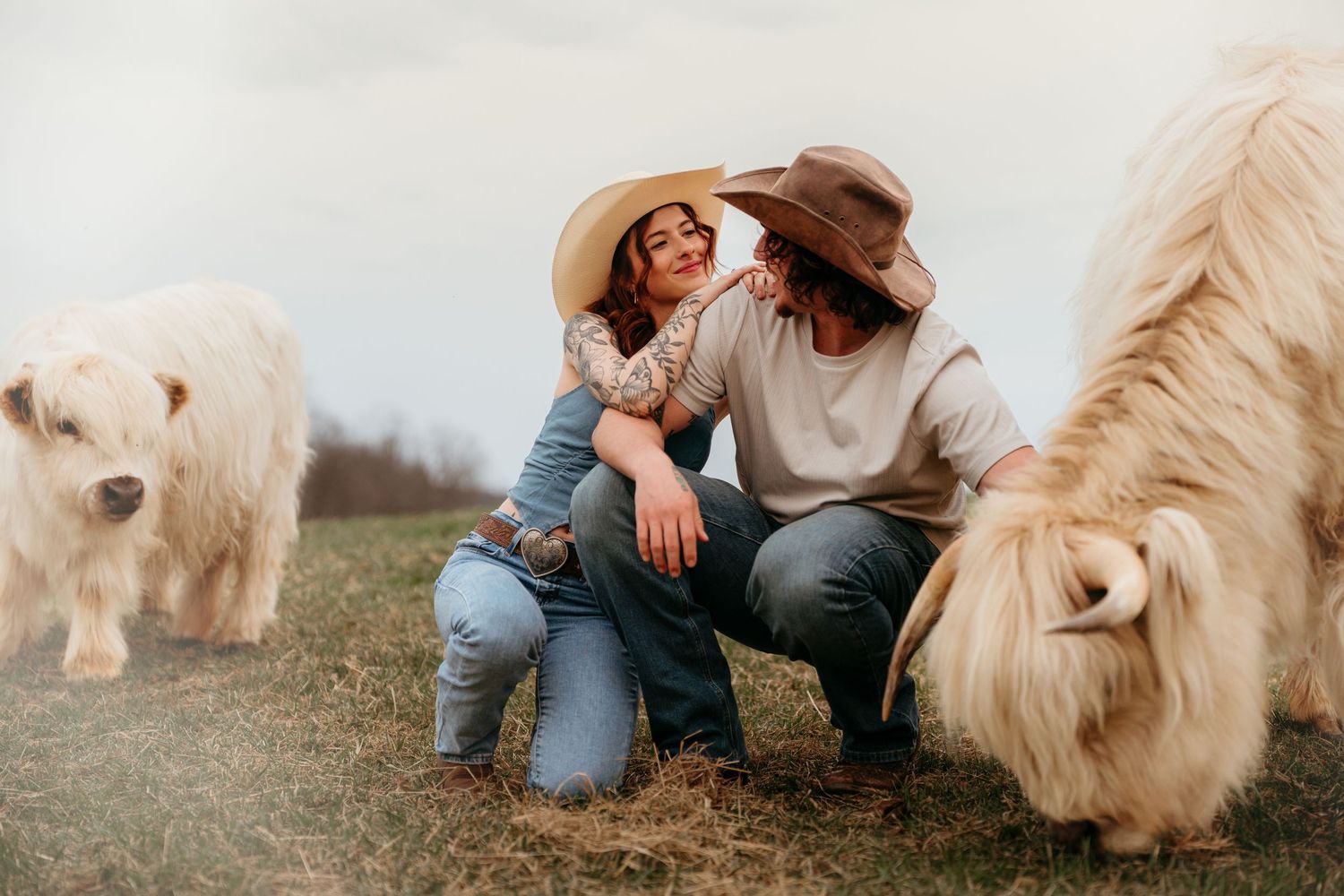 Casual outdoor picnic scene with couple relaxing on blanket as cream-colored horse grazes nearby.