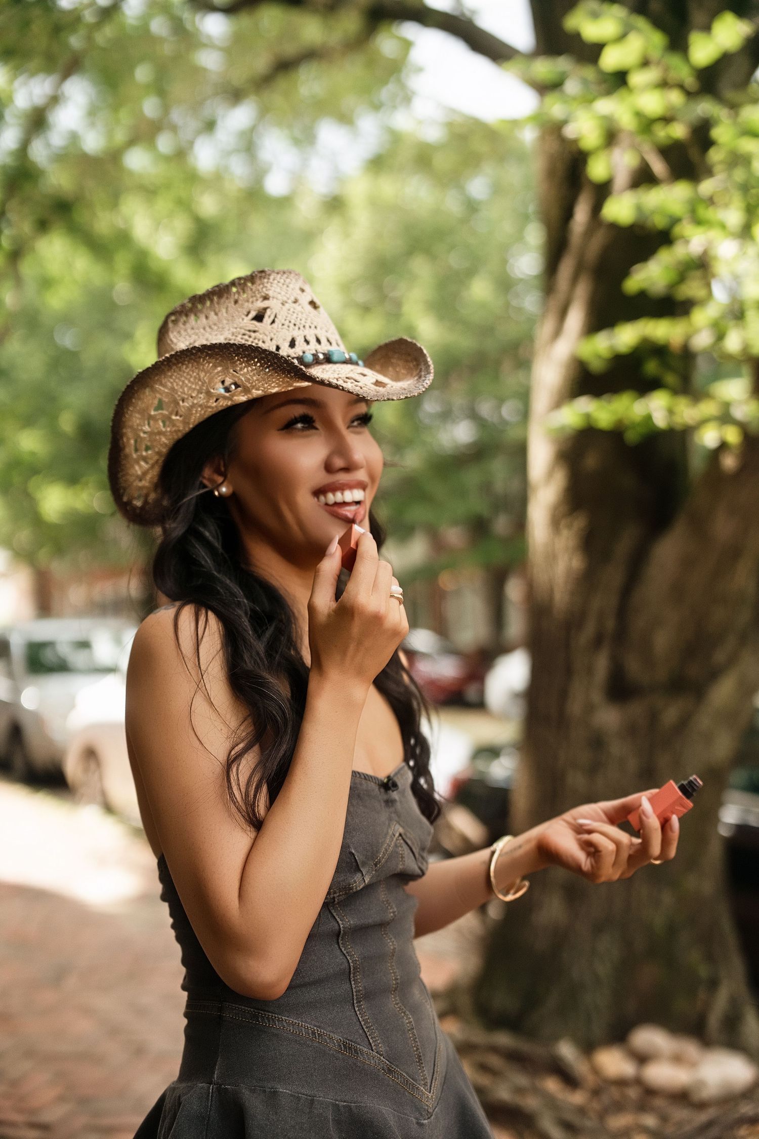 A stylish western look featuring a straw cowboy hat and denim overalls in a sunny outdoor setting.