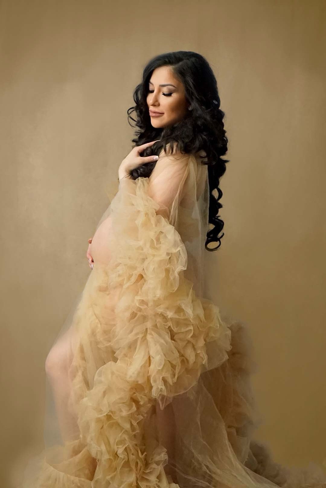 Ethereal maternity photoshoot featuring flowing champagne-colored tulle fabric against a neutral backdrop.
