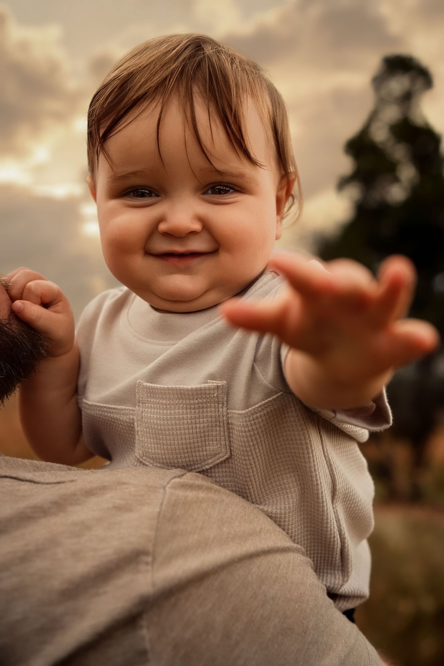 baby in a gray and white outfit making playful expressions outdoors at sunset in Manassas Battlefield National Park