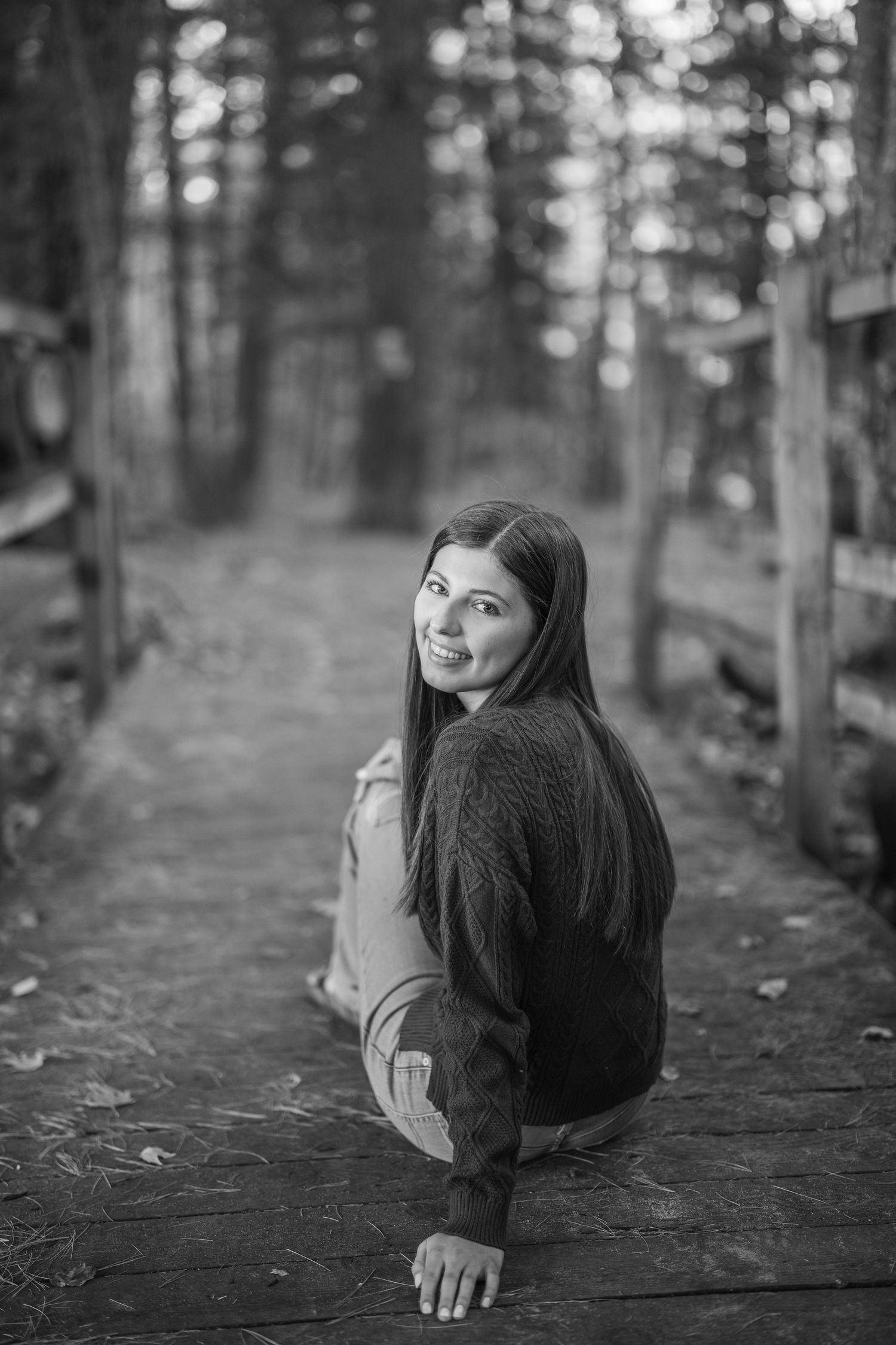 A series of black and white photos showing a person in a sweater sitting on a fallen log in a misty forest.