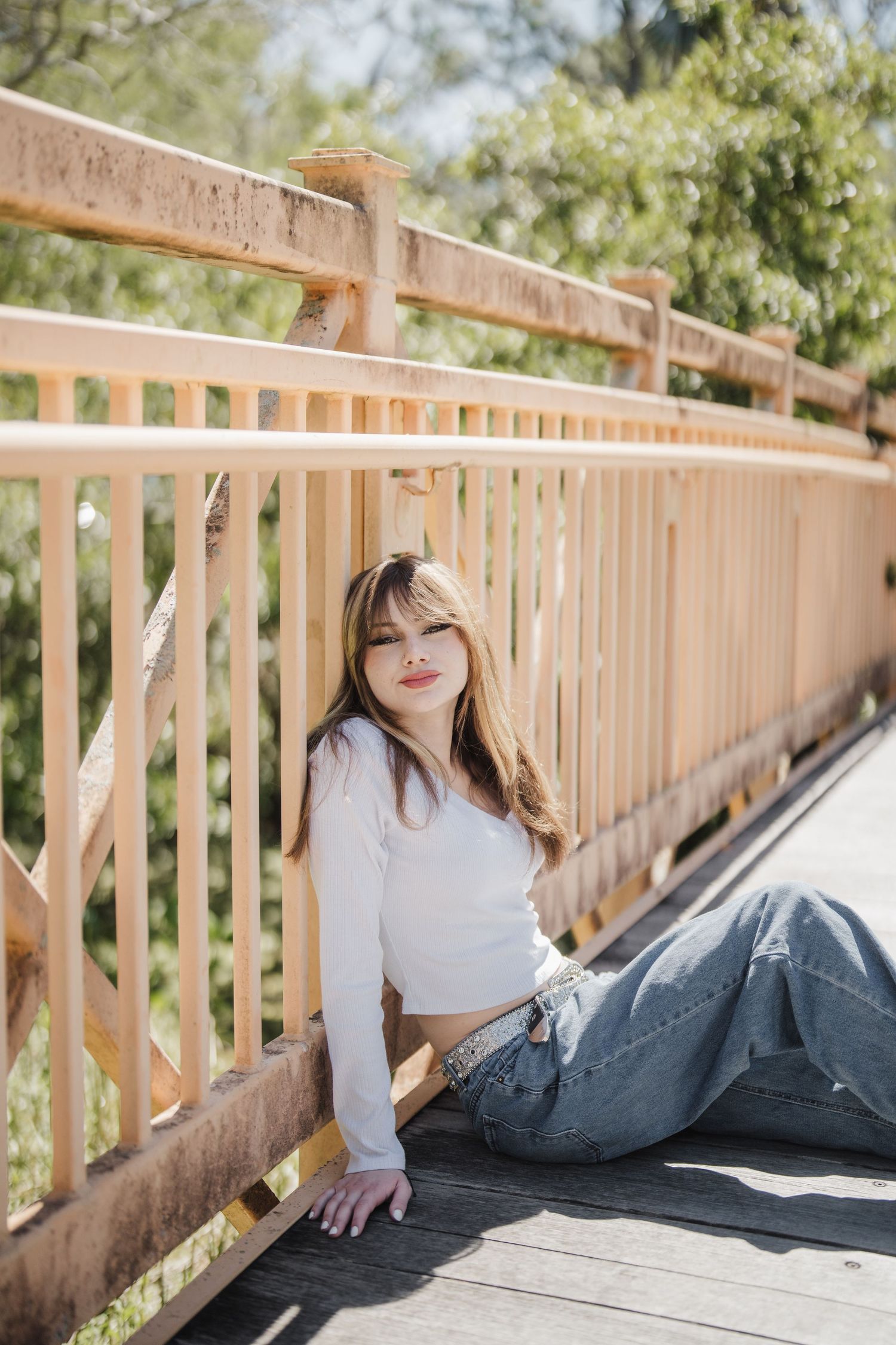 Person in casual attire lounging on a wooden deck with natural lighting and greenery in the background.