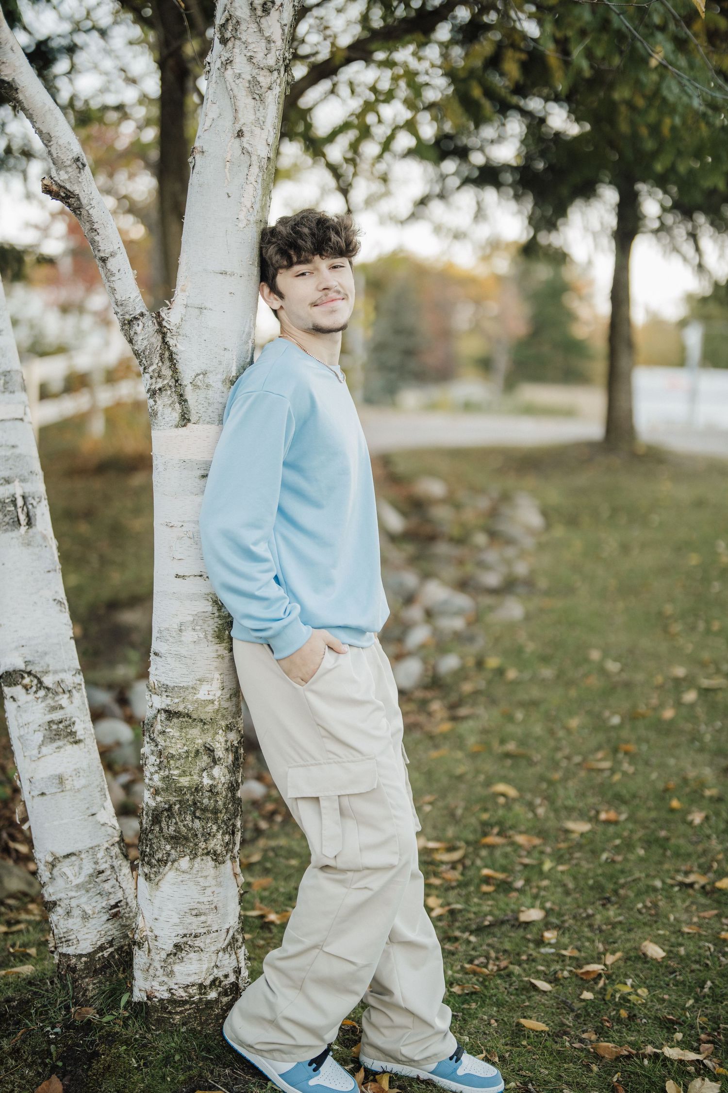 A series of outdoor portraits taken near birch trees on grass with fallen autumn leaves.