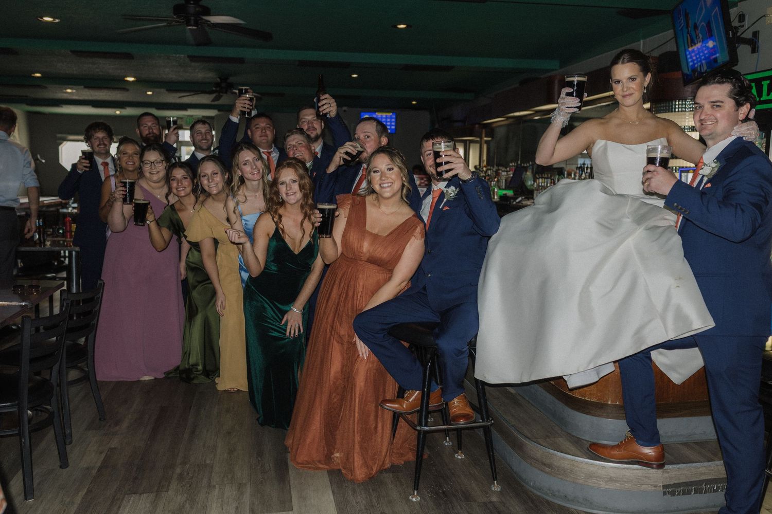 Wedding reception dance floor filled with guests celebrating in a dimly lit venue.