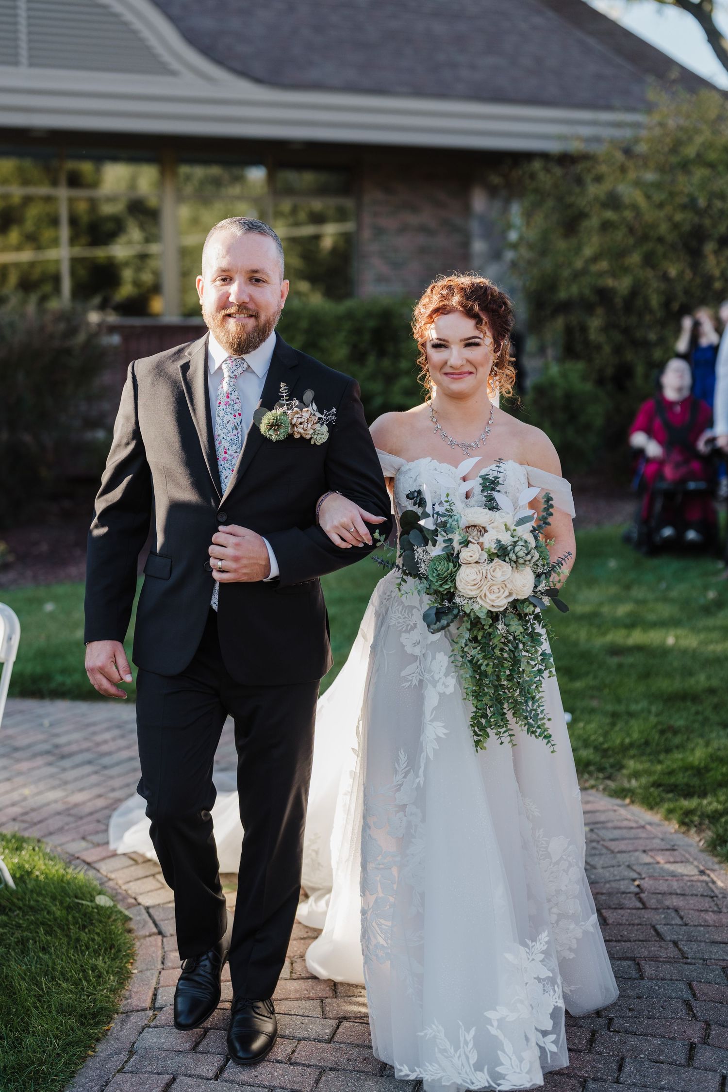 Couple walks together on brick pathway during outdoor wedding ceremony.