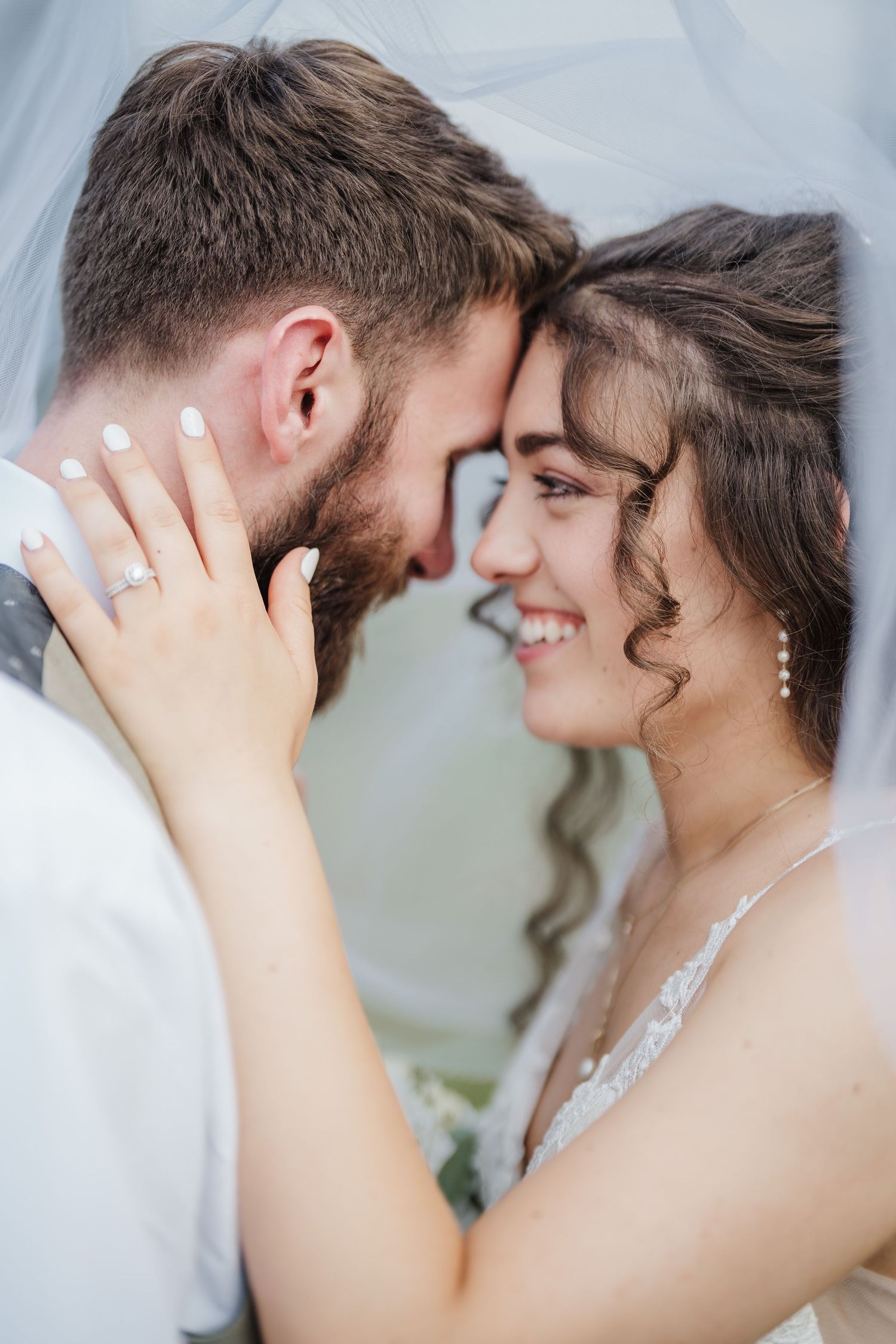 Close-up intimate moment between newlyweds under a veil.