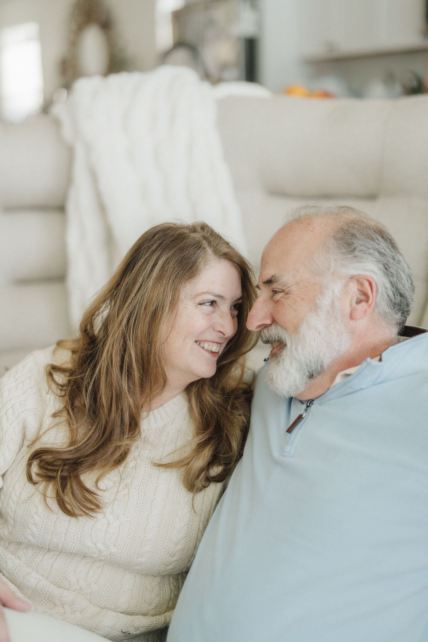 A young woman in a white sweater shares a tender moment with an elderly man in a blue shirt.