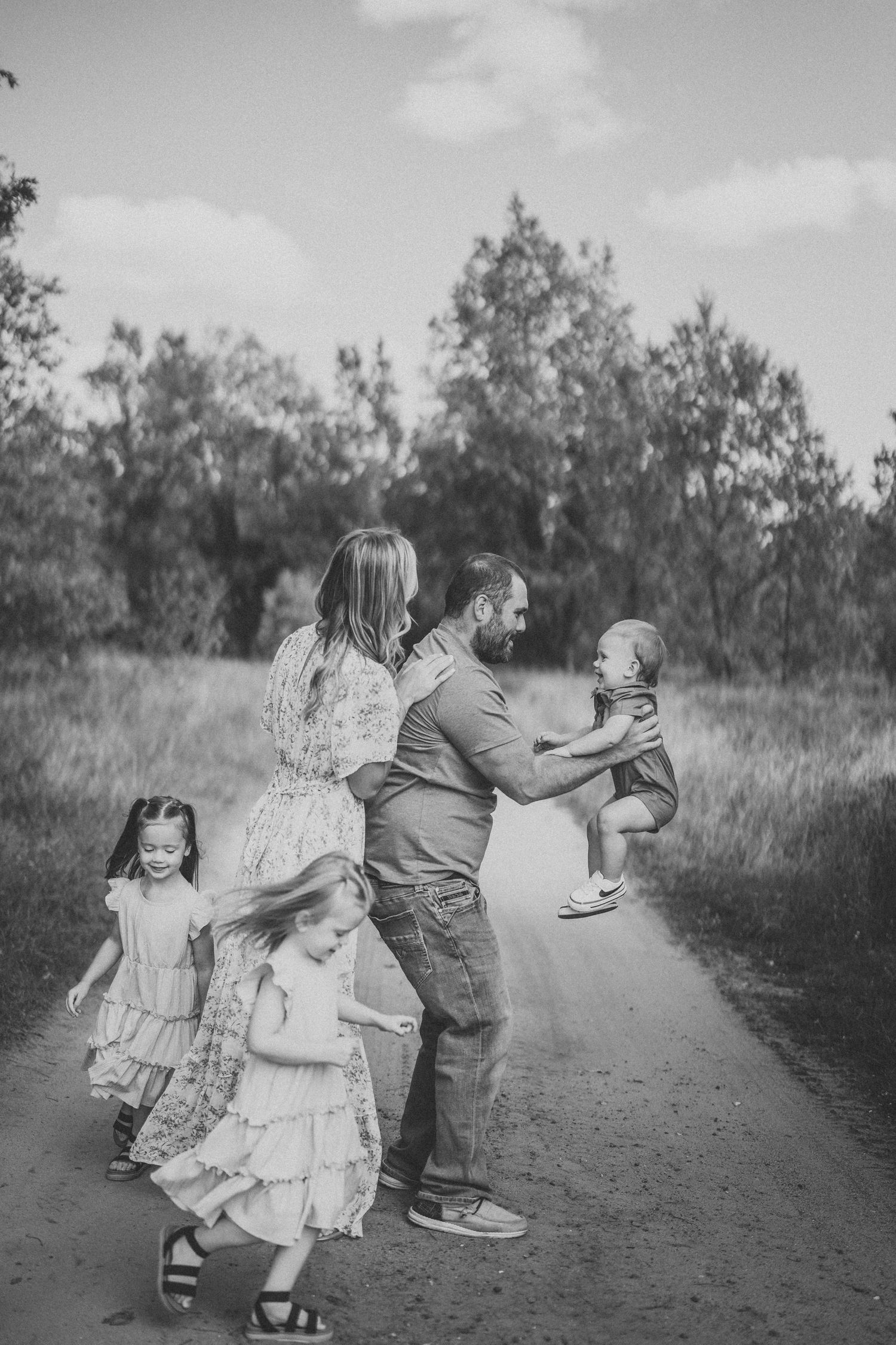 Black and white photo captures playful moments on a rural path with coordinated outfits.