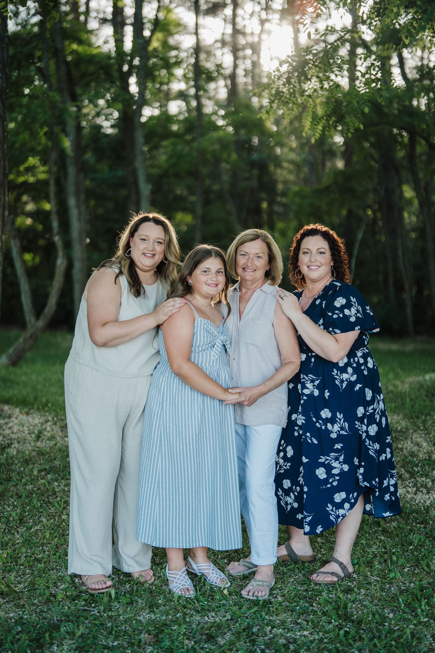 A group in coordinating blue and white outfits sits together on grass during an outdoor photo session.
