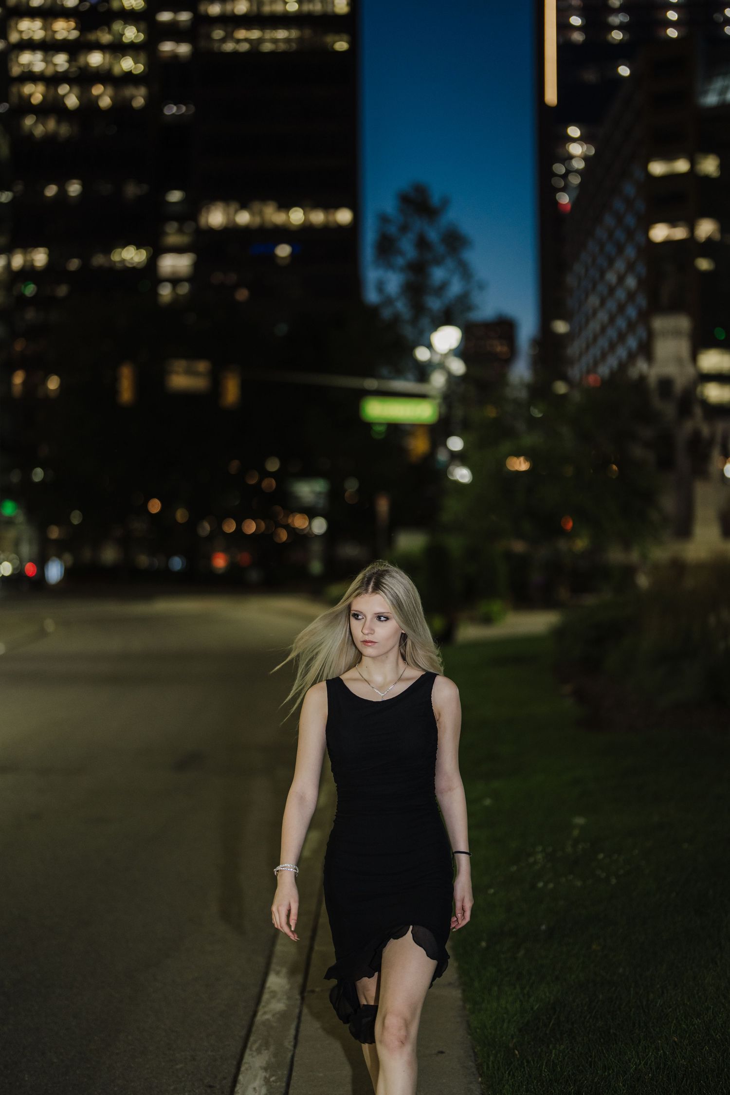 Dramatic evening cityscape with tall buildings and street lights creating an urban ambiance.