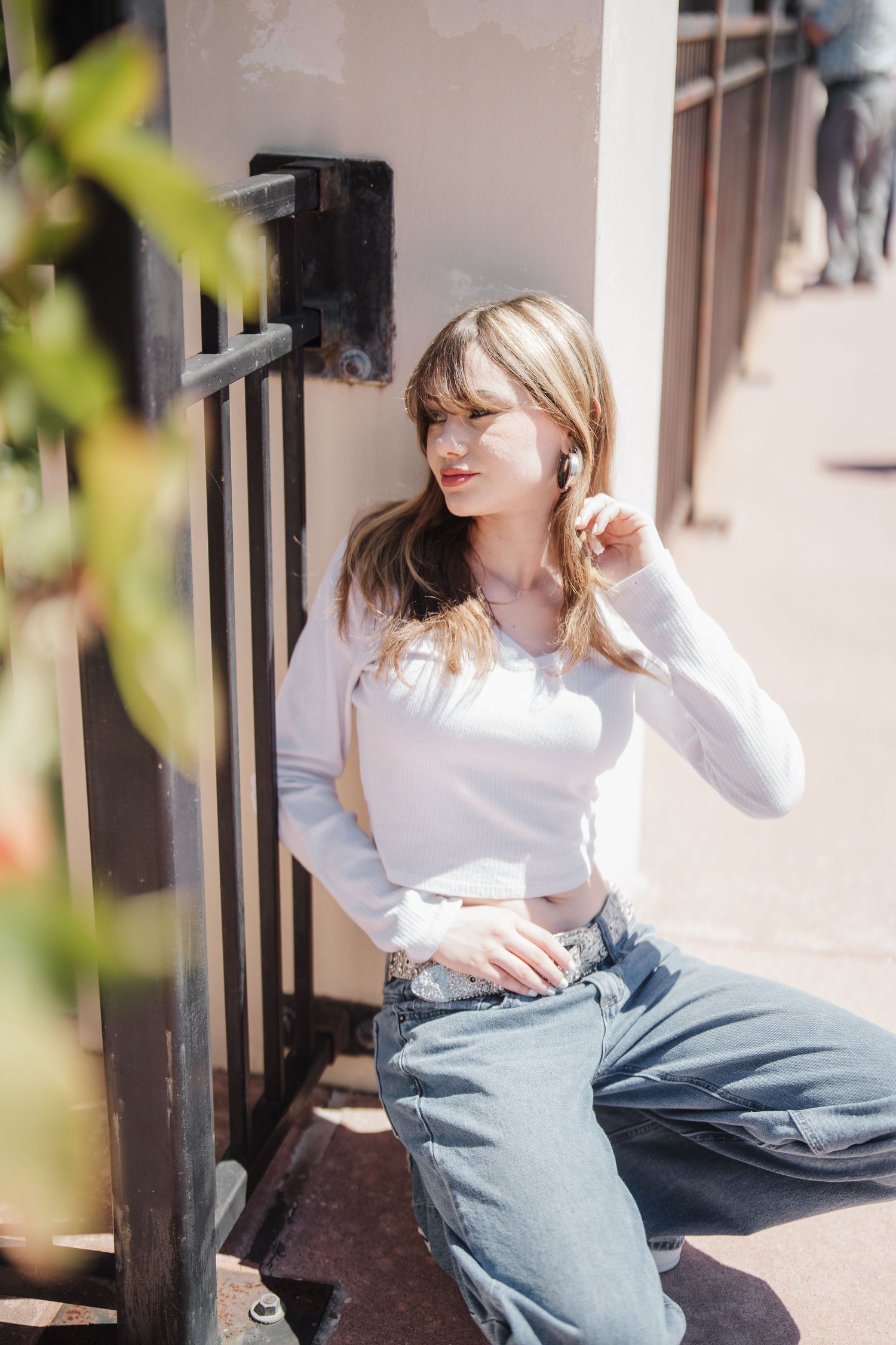Casual denim and white outfit captured in natural light on an outdoor porch with greenery.