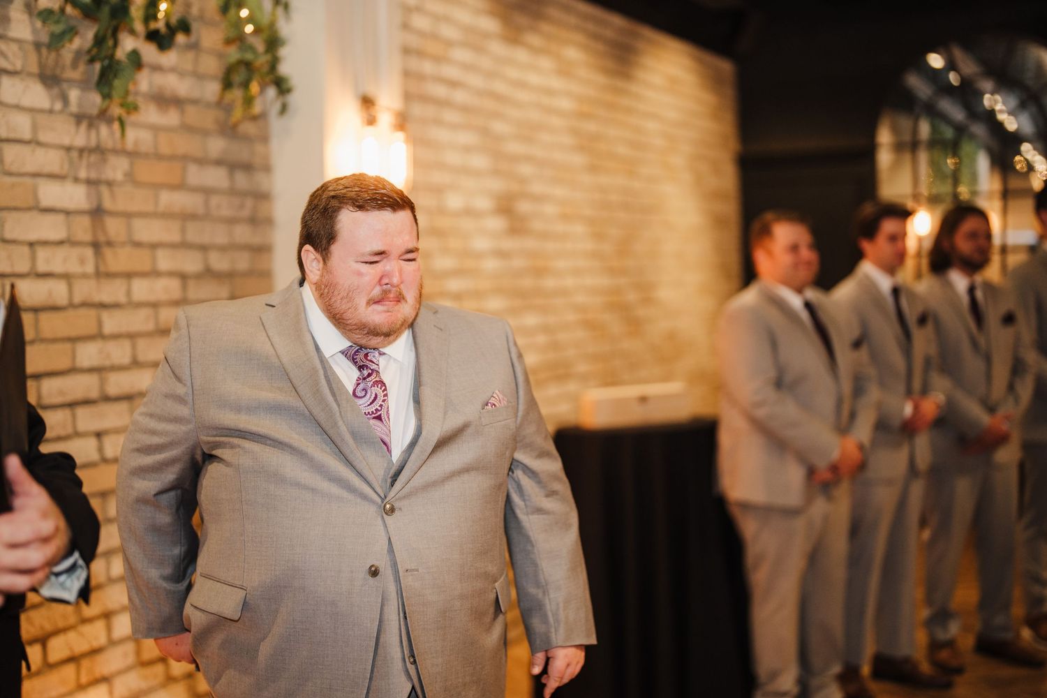 A candid moment at a wedding venue with groomsmen wearing matching gray suits.