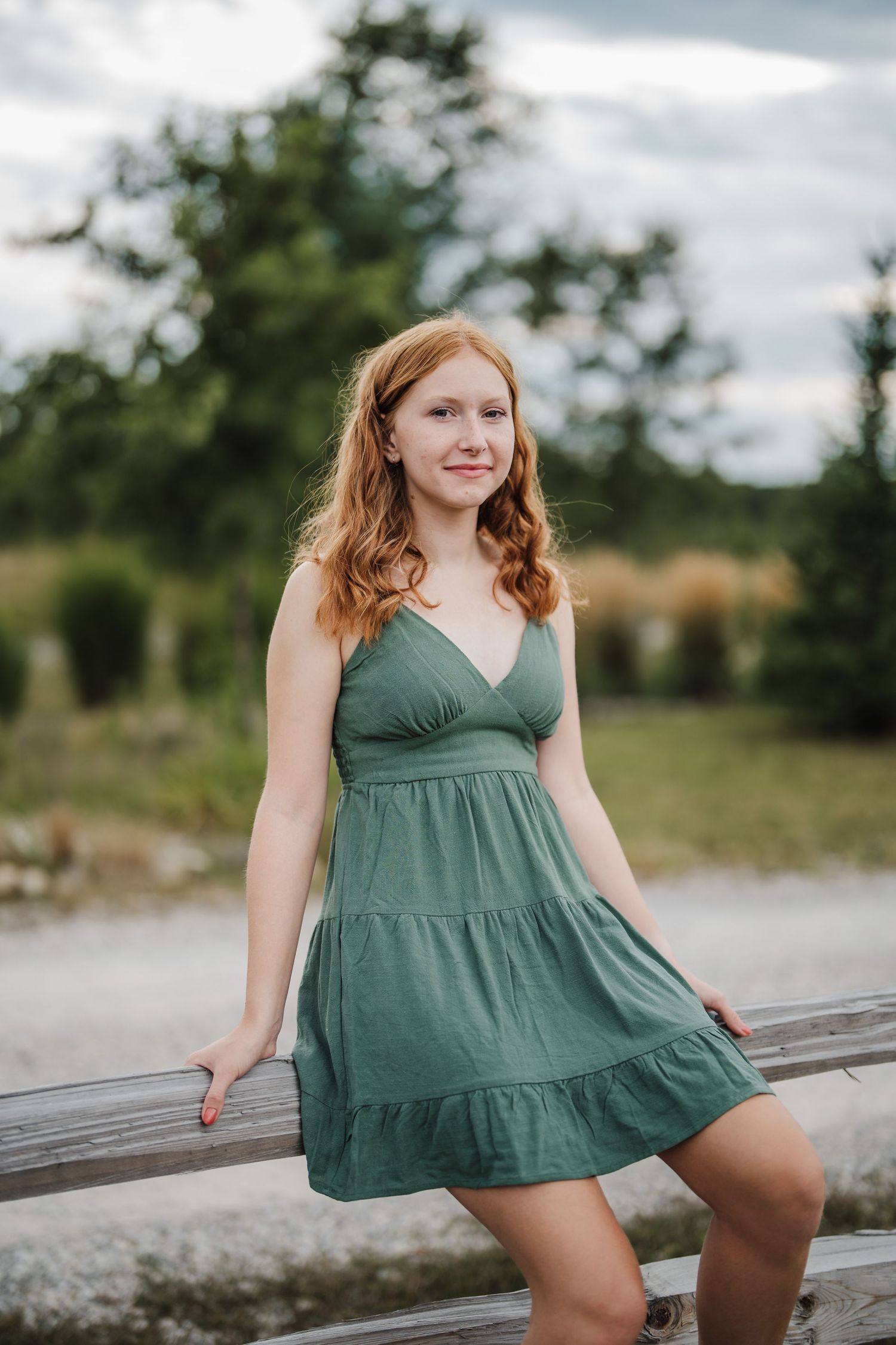 A flowing green tiered sundress twirls gracefully in an outdoor setting with natural scenery in the background.